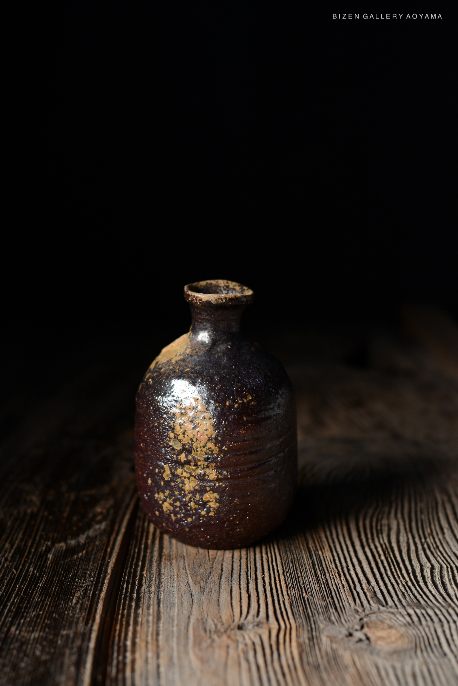 暗い背景の前に置かれた、陶器の壺。独特な模様と色合いが特徴的で、木のテーブルの上に置かれている。