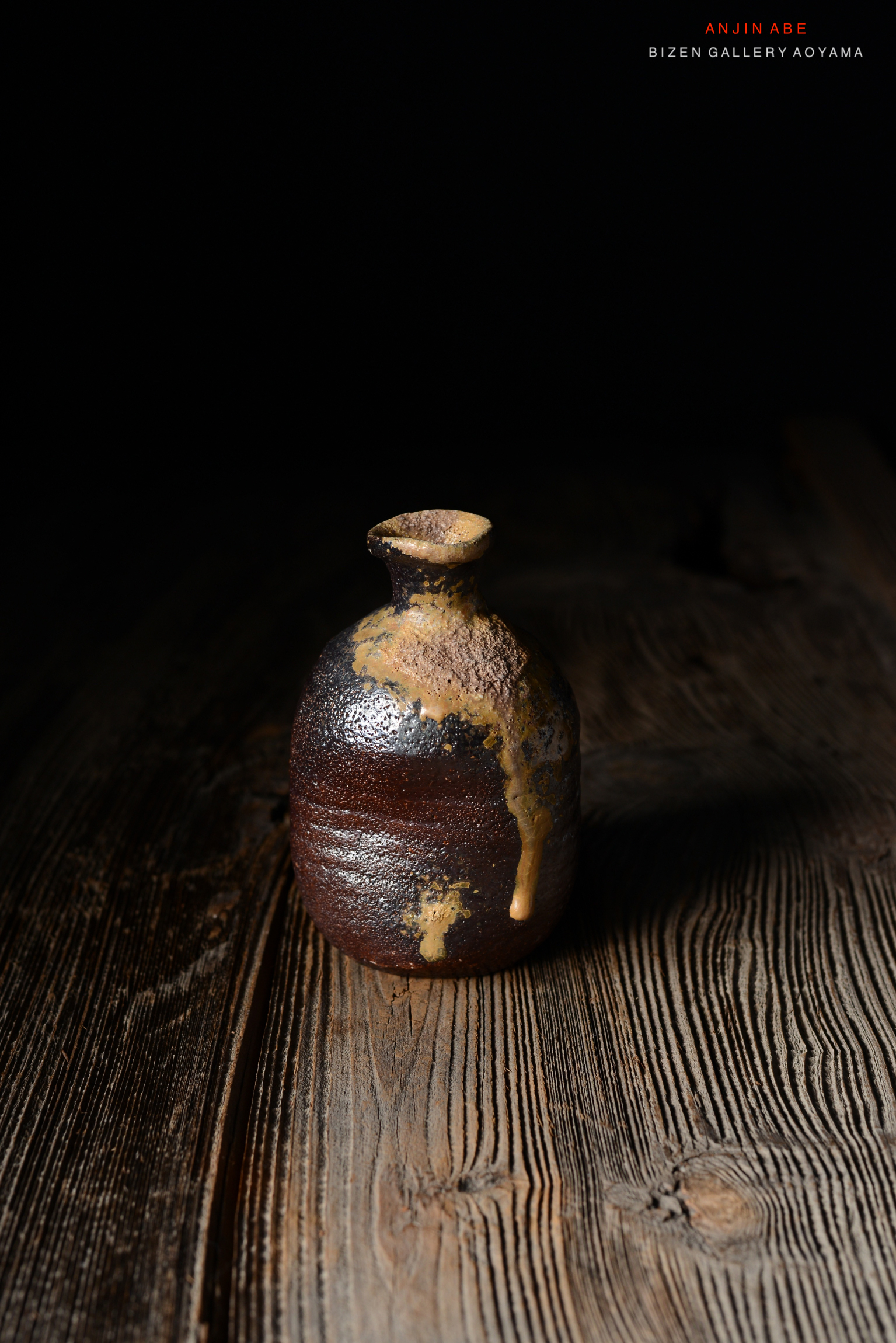 暗い背景の上に置かれた陶器の壺。釉薬の滴が垂れた質感が特徴的。