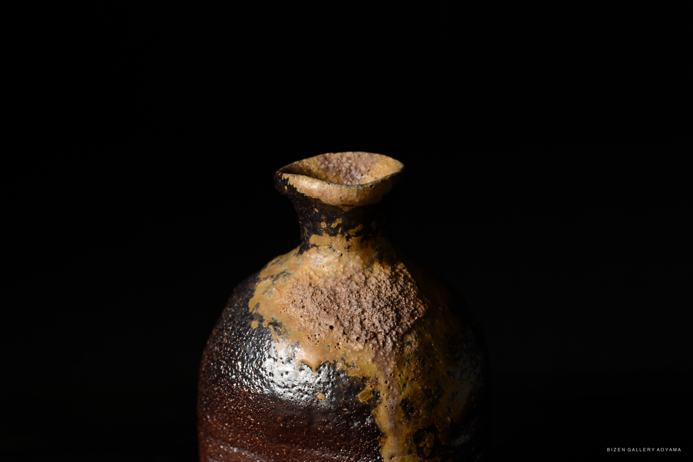 黒い背景に置かれた独特な形の陶器の壺。