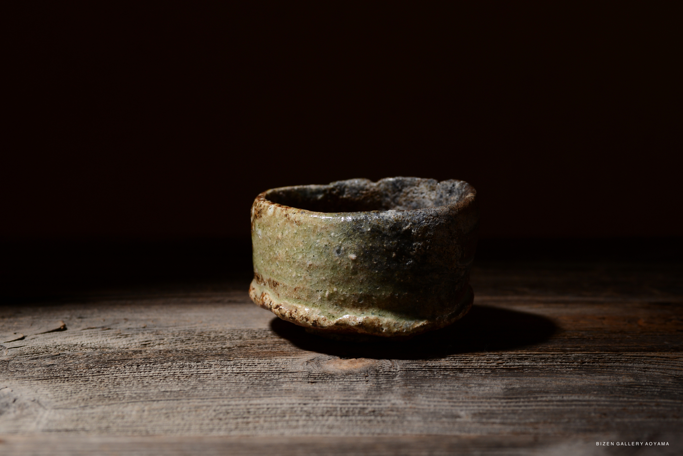 テーブル上の土製の器、緑色と茶色の釉薬が施されている。
