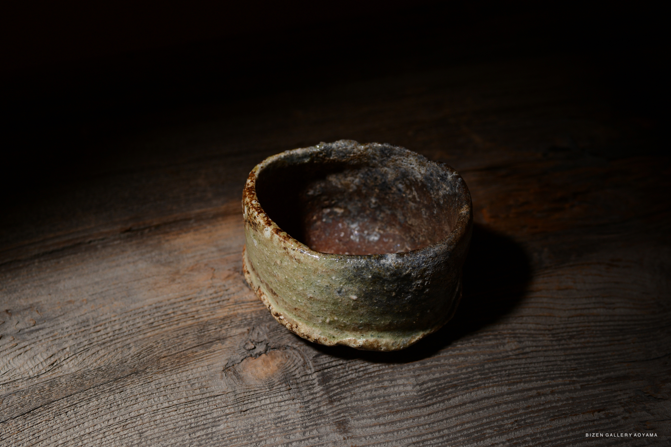 古い陶器の器が木のテーブルの上に置かれている。