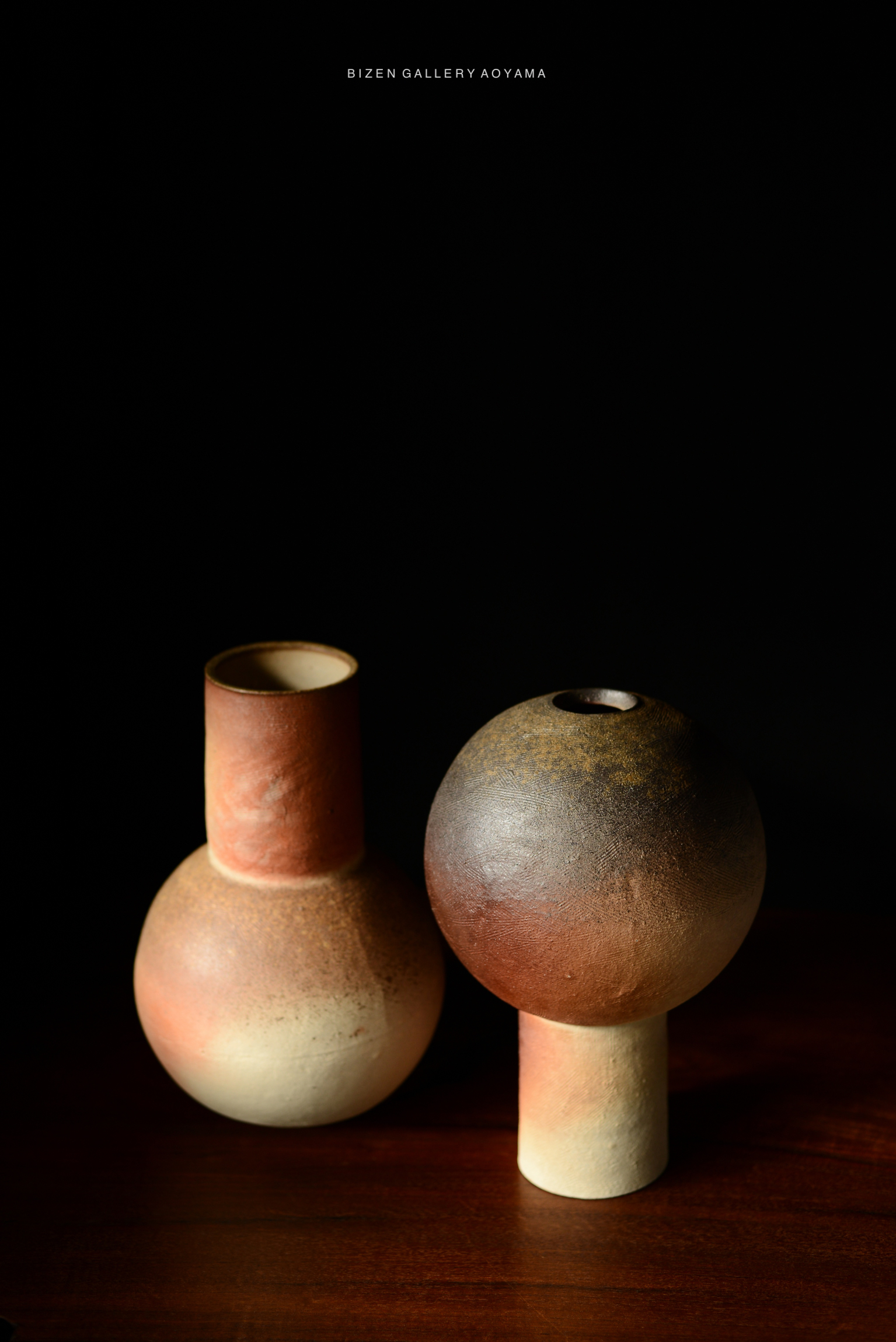 Two ceramic vases with a range of earthy colors, placed on a wooden surface against a black background.