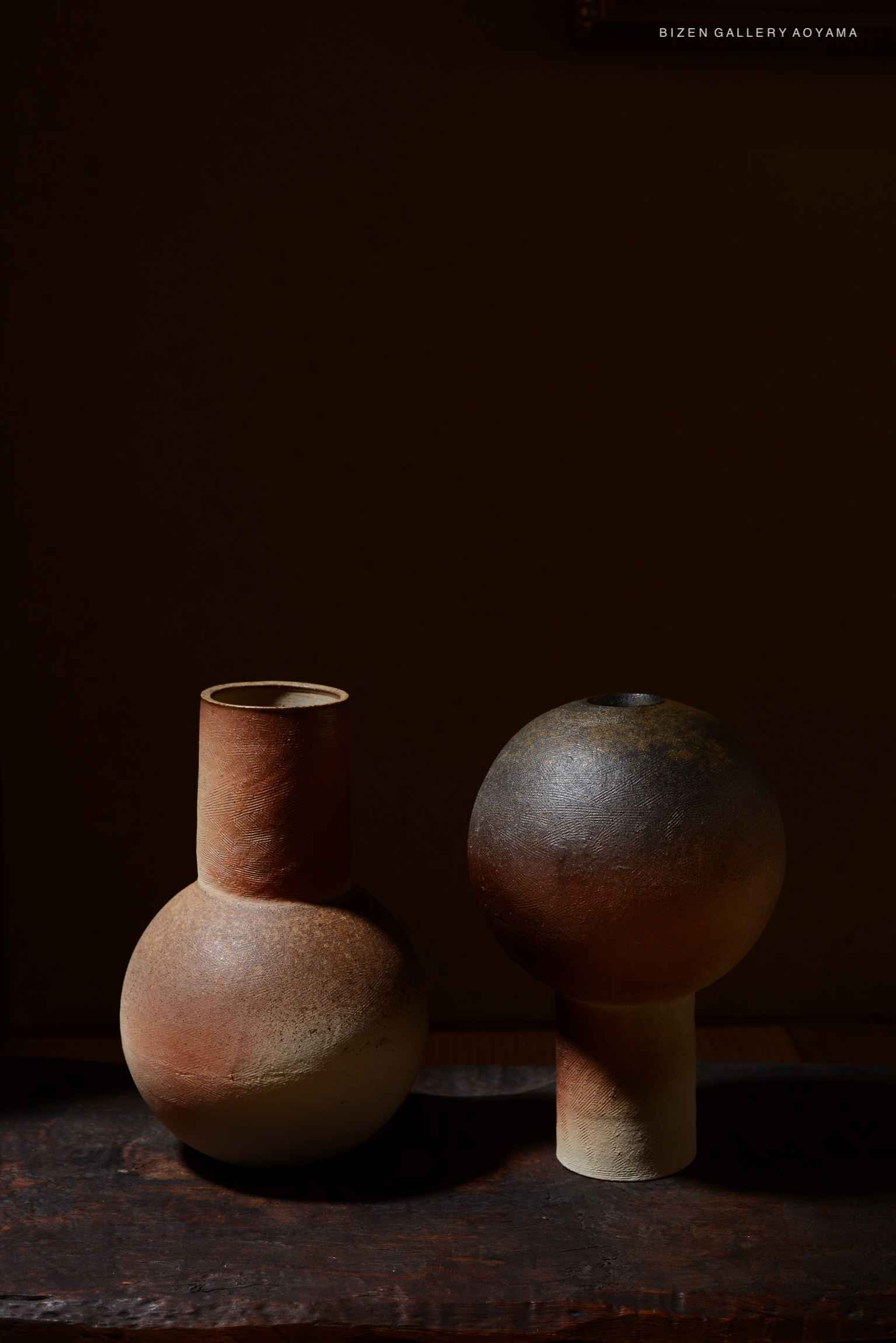 Two ceramic vases with distinct shapes and earthy tones, set against a dark background.