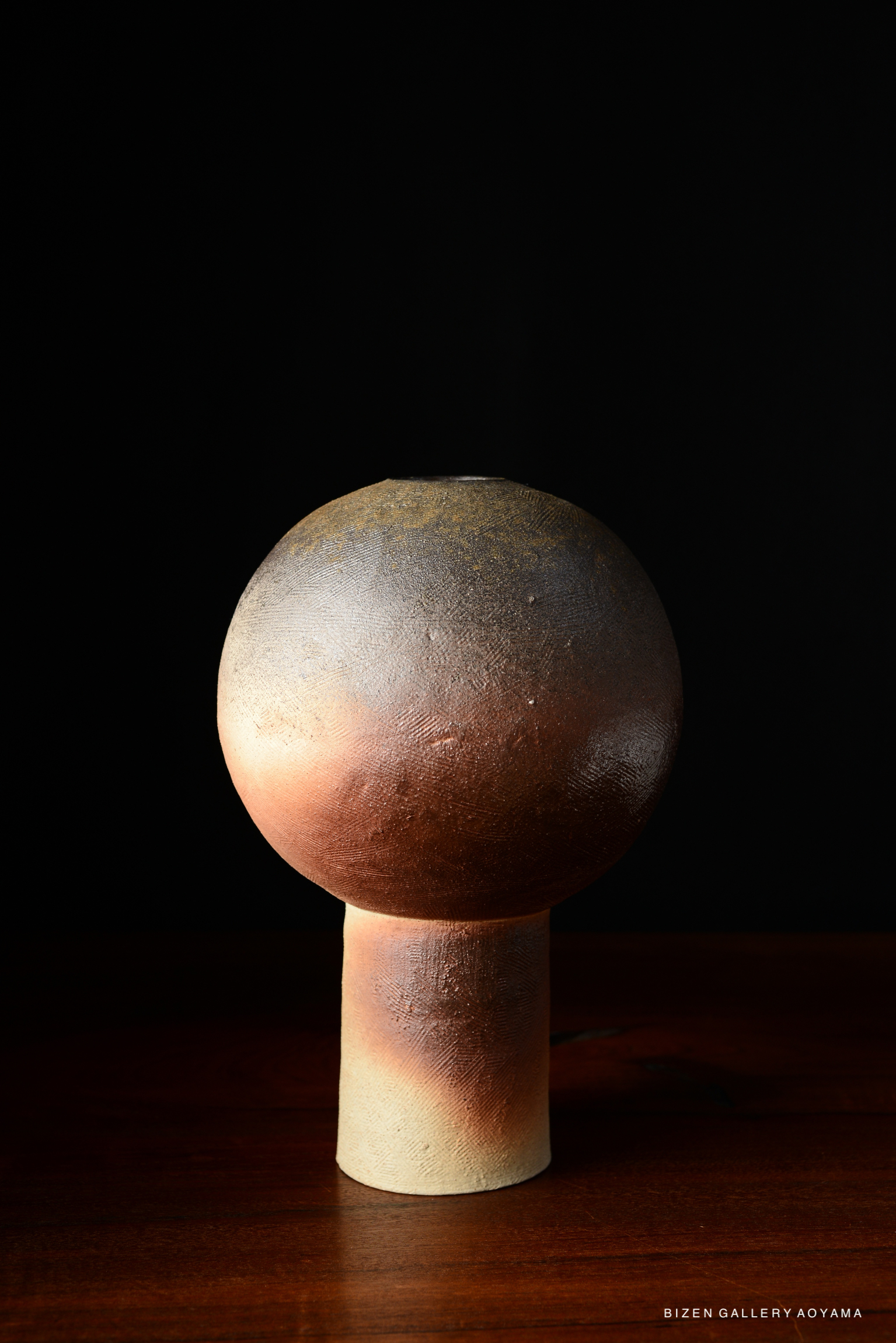 A ceramic lamp with a spherical shade and a cylindrical base, set against a dark background.