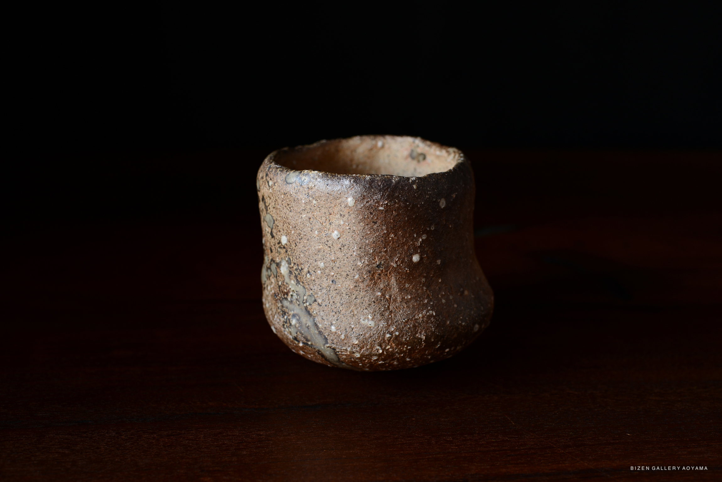 土器の背景が黒い木材のテーブルの上に置かれている。