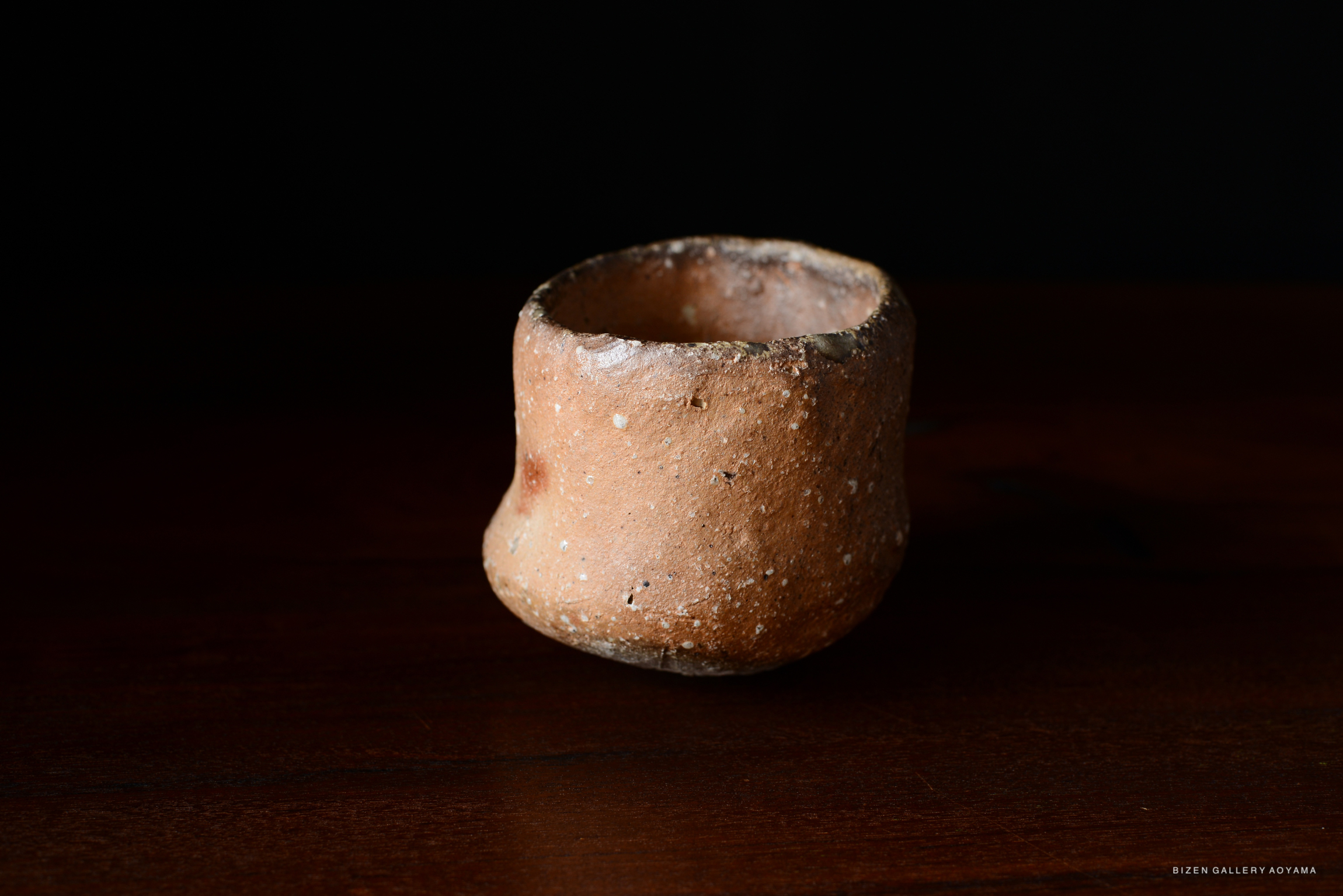 凹んだ形状の素焼きの陶器が、黒い背景の上に置かれている。