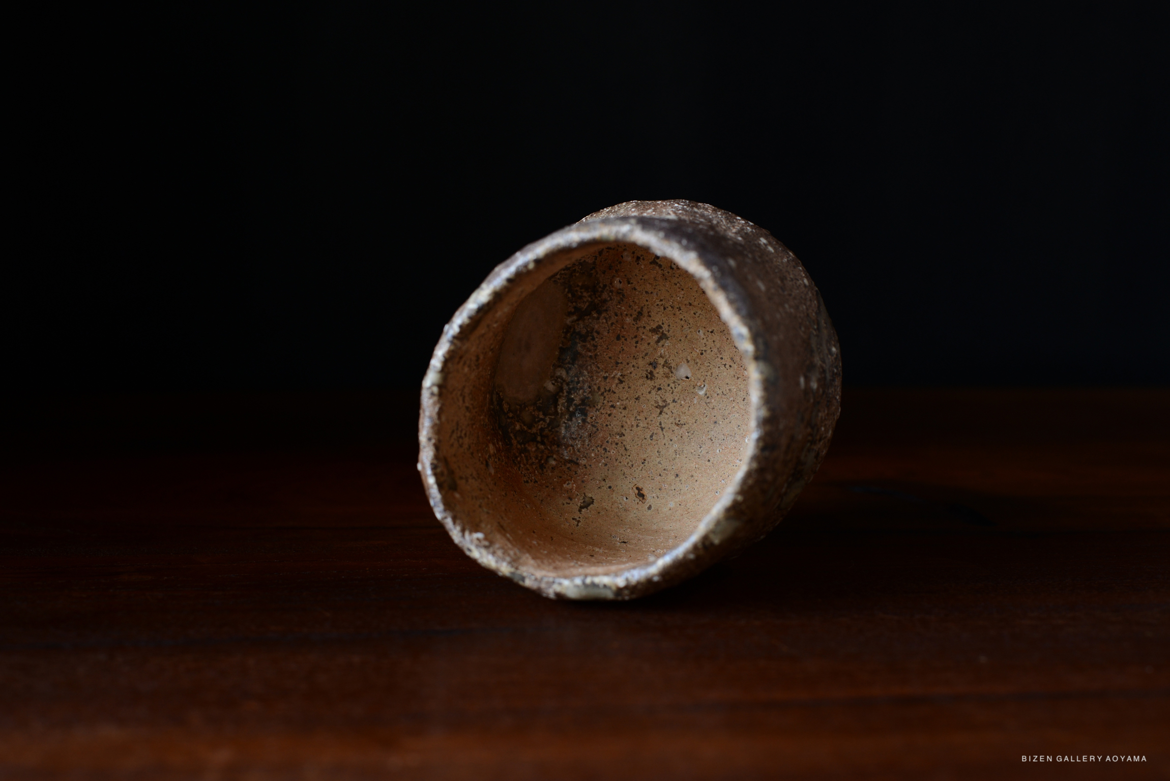 木のテーブルの上に置かれた、内側が滑らかな素朴な陶器の器