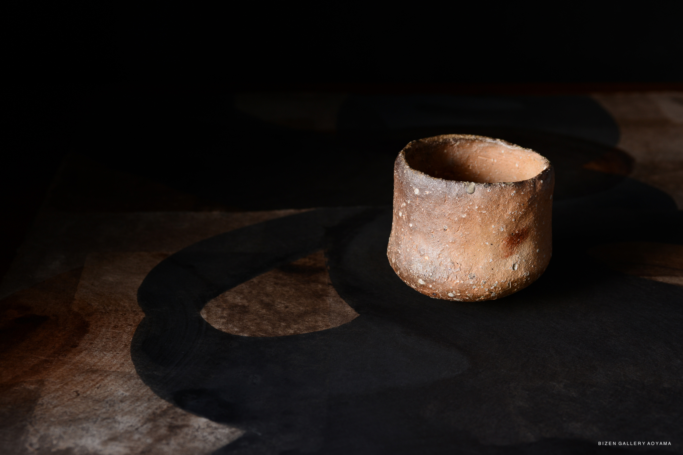 黒い背景の上に置かれた素焼きの茶碗