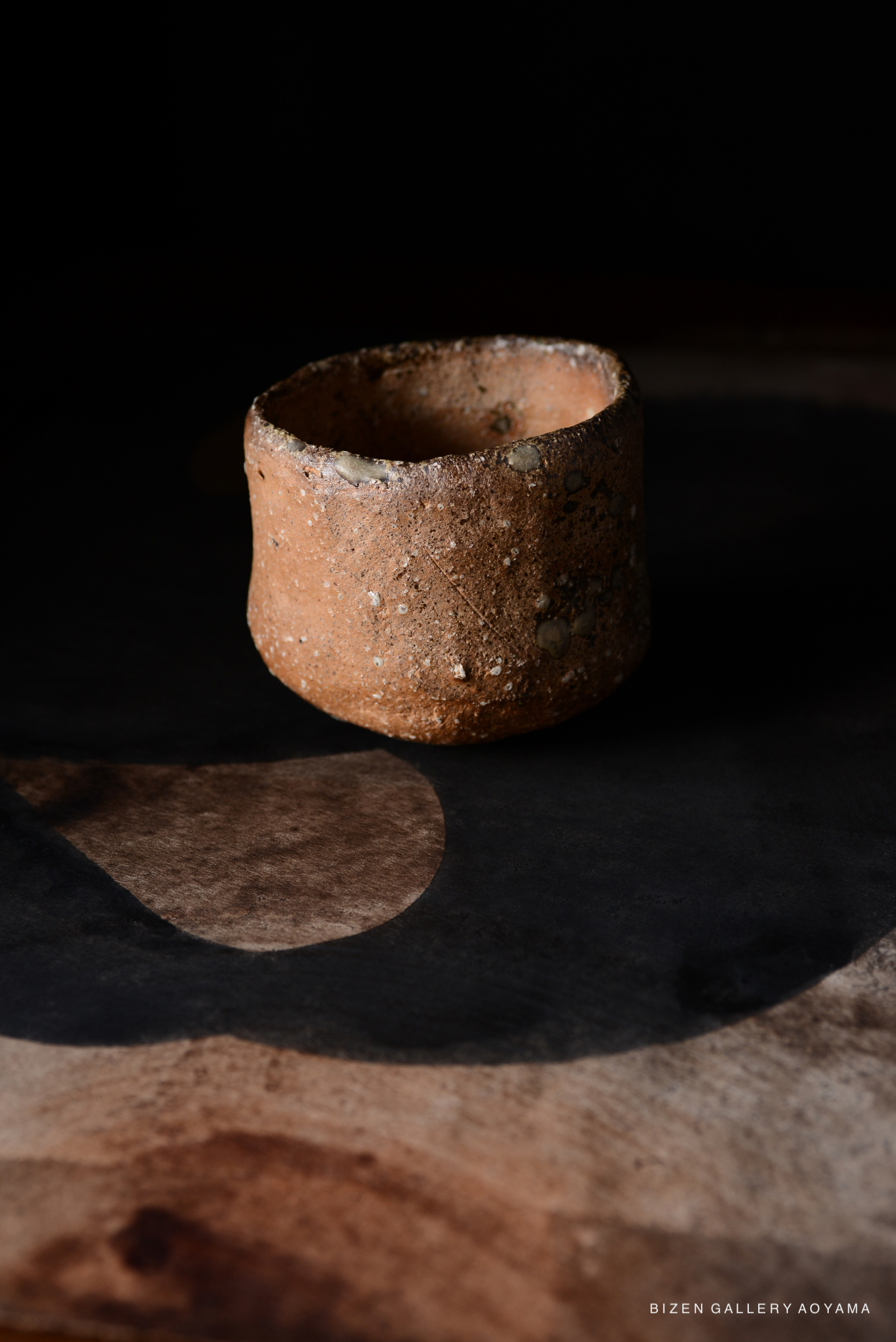 黒背景に置かれた独特な形の備前焼の茶碗