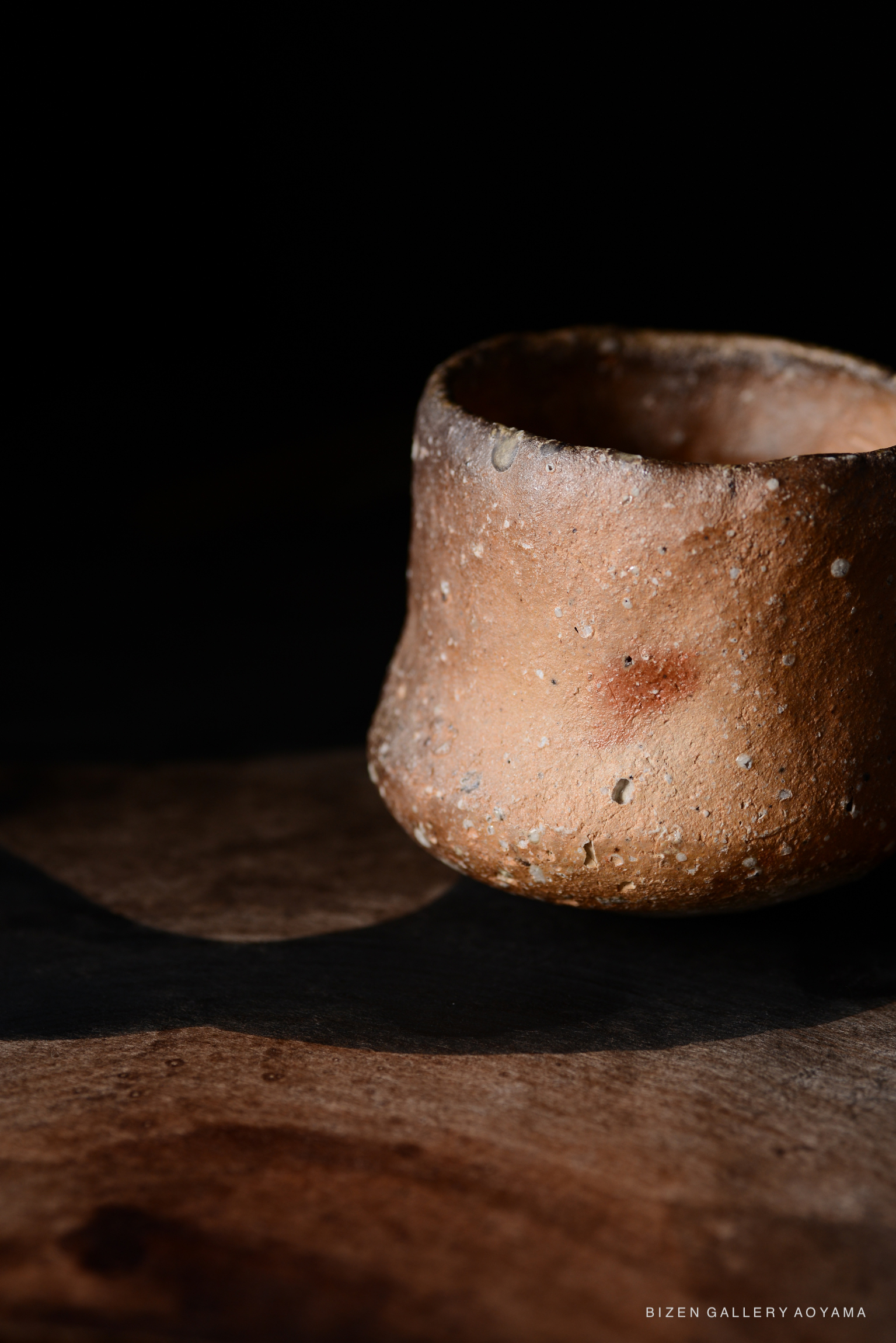 黒い背景の前にある、質感のある焼き物の器のクローズアップ
