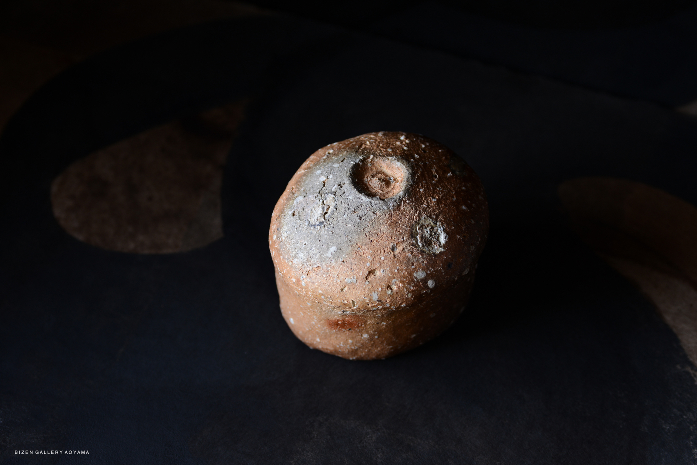 陶器の素焼きの球体のようなオブジェクトが、暗い背景の上に置かれている