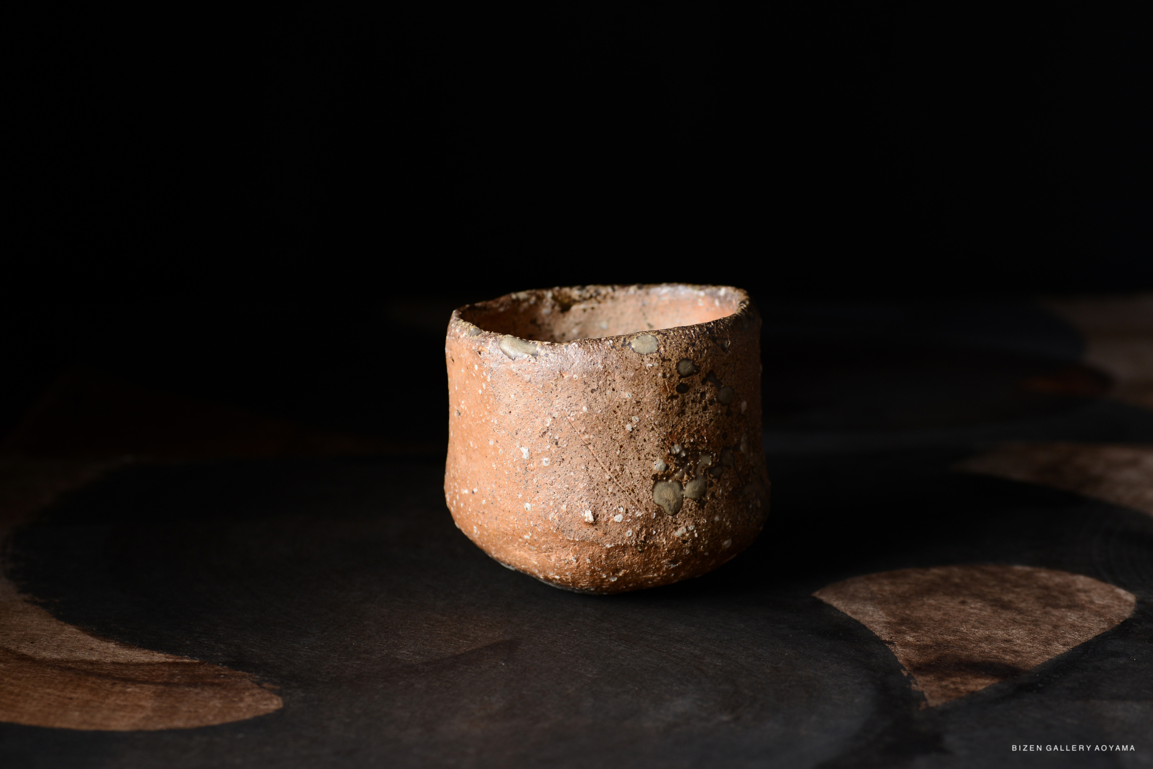 黒い背景の上に置かれた素焼きの陶器のカップ