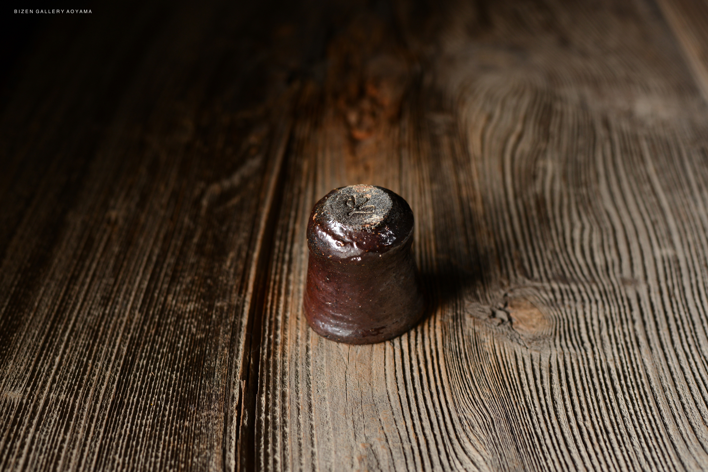 古い灰色の陶器の器が木のテーブルの上に置かれている。