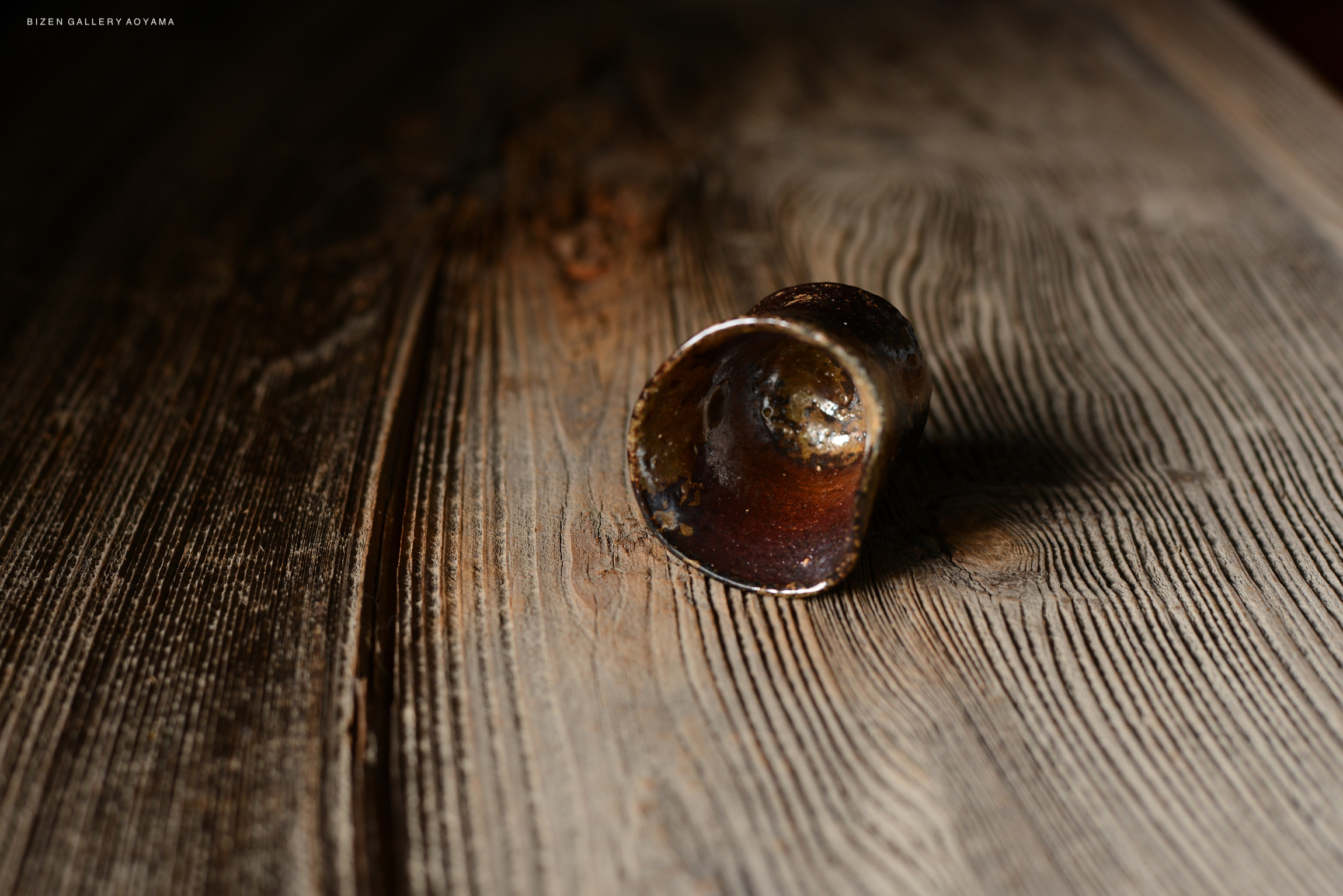 木のテーブルの上に置かれたこげ茶色の陶器の器