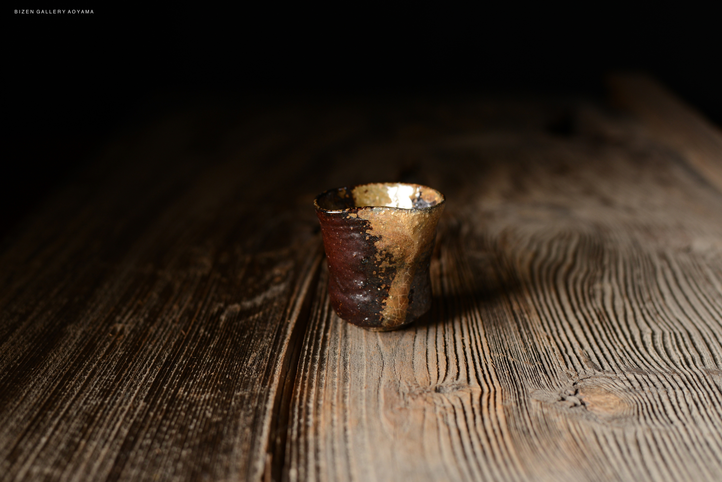 暗い背景の上に置かれた、陶器の美しい質感を持つ小さなカップ。木のテーブルの上で強調されています。