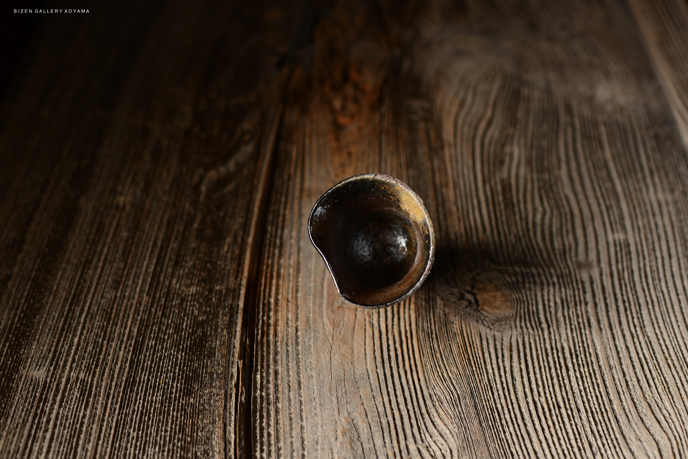 木目のあるテーブルの上に置かれた小さな陶器の器