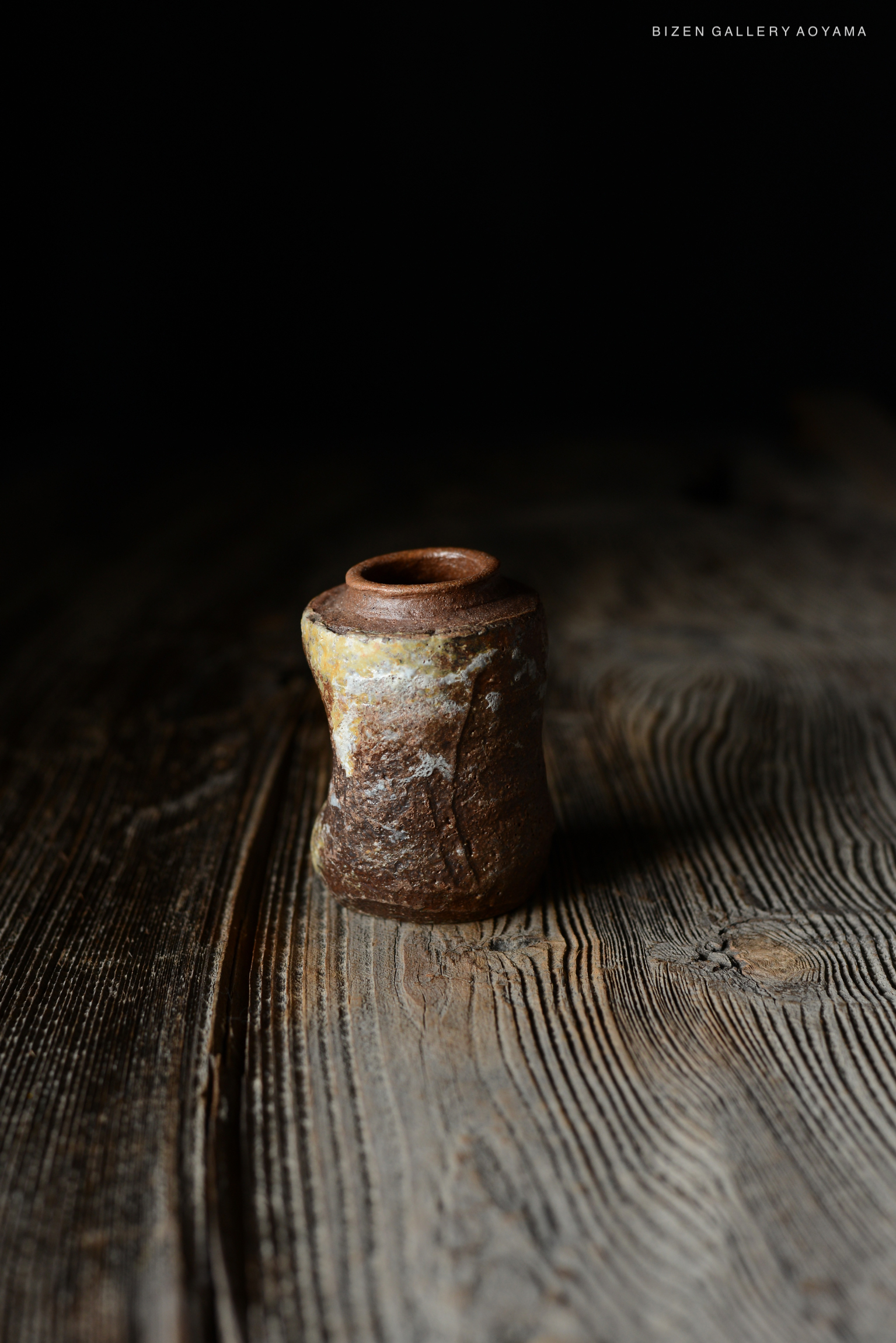 木のテーブルの上に置かれた独特な形状の陶器の花瓶