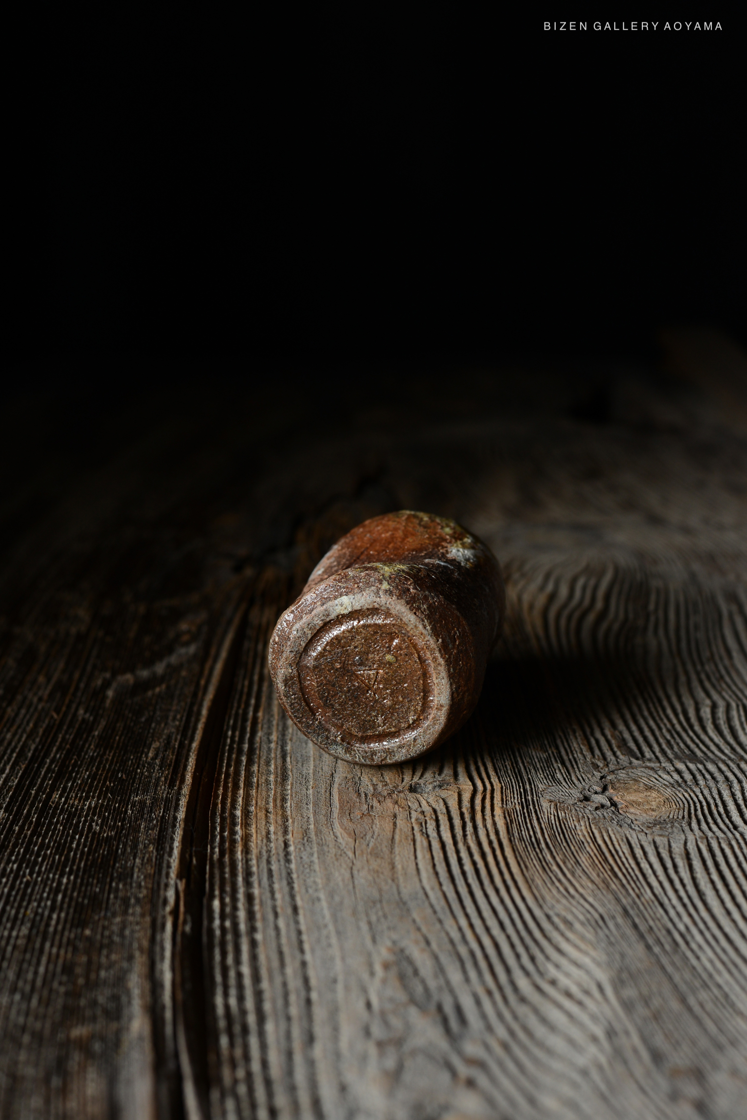 黒い背景の上に置かれた陶器の器が、木のテーブルに置かれている