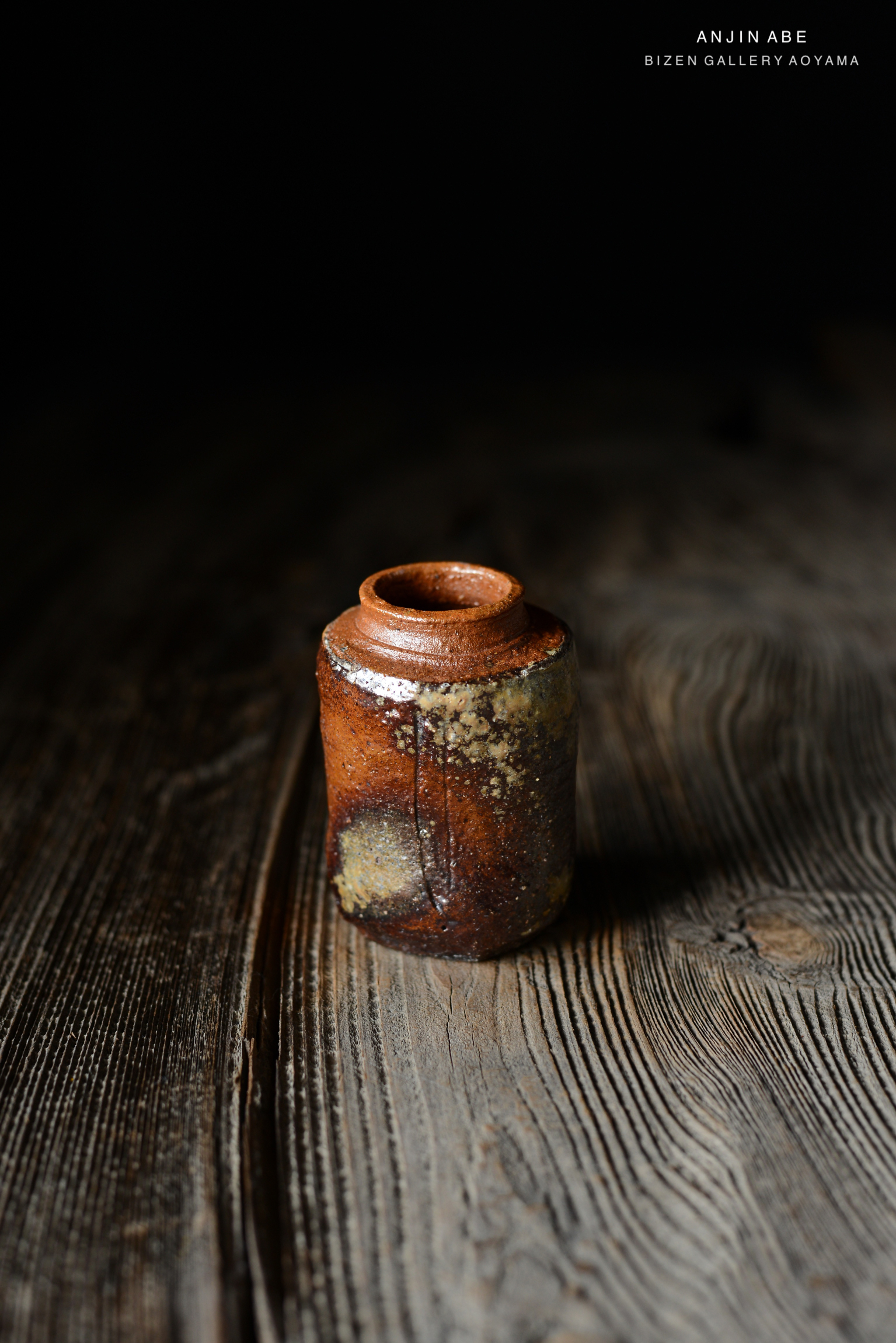 木のテーブルの上に置かれた、美しい陶器の瓶。土の質感と多様な色合いが特徴。