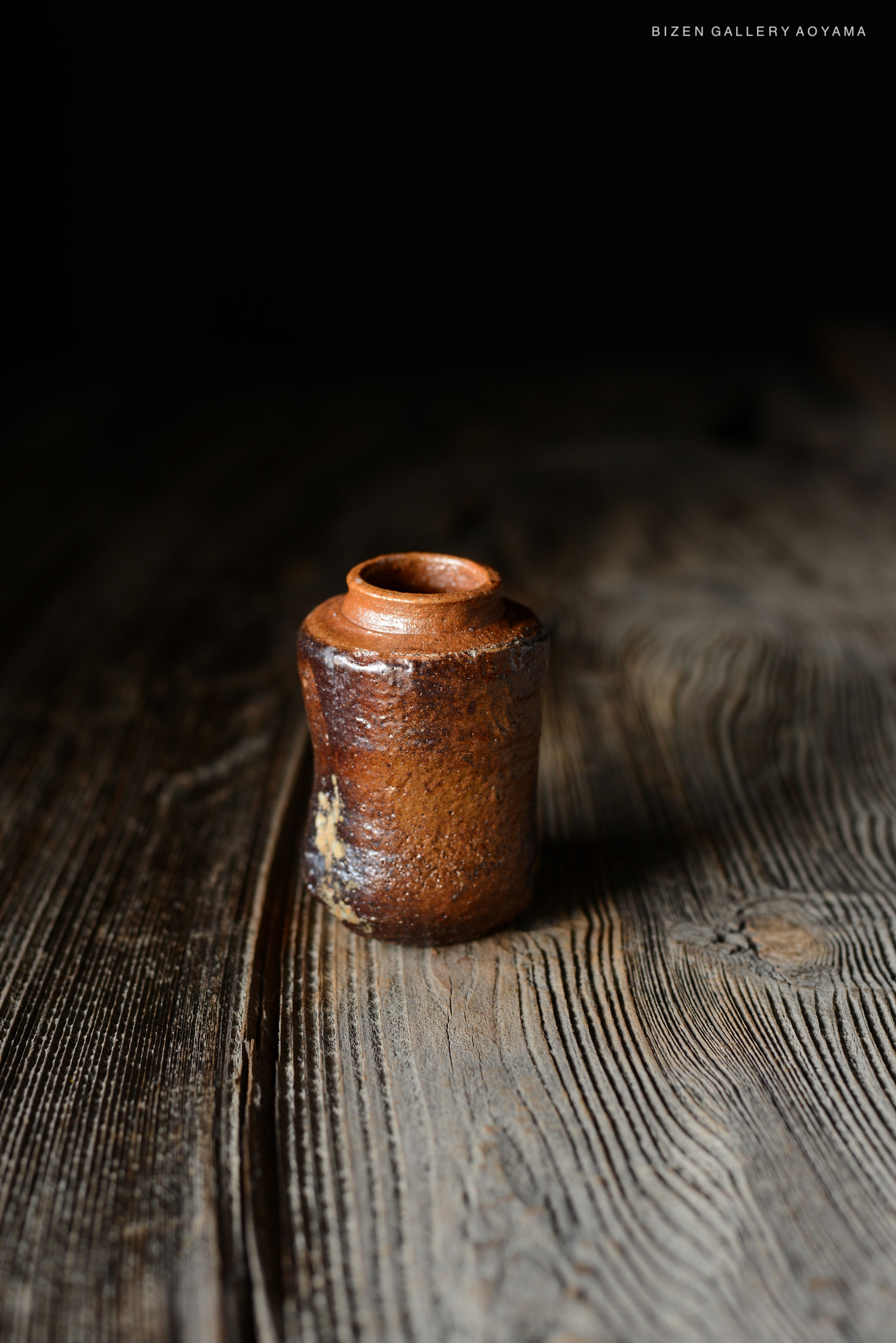 木のテーブルの上に置かれた小さな茶色の陶器の壺