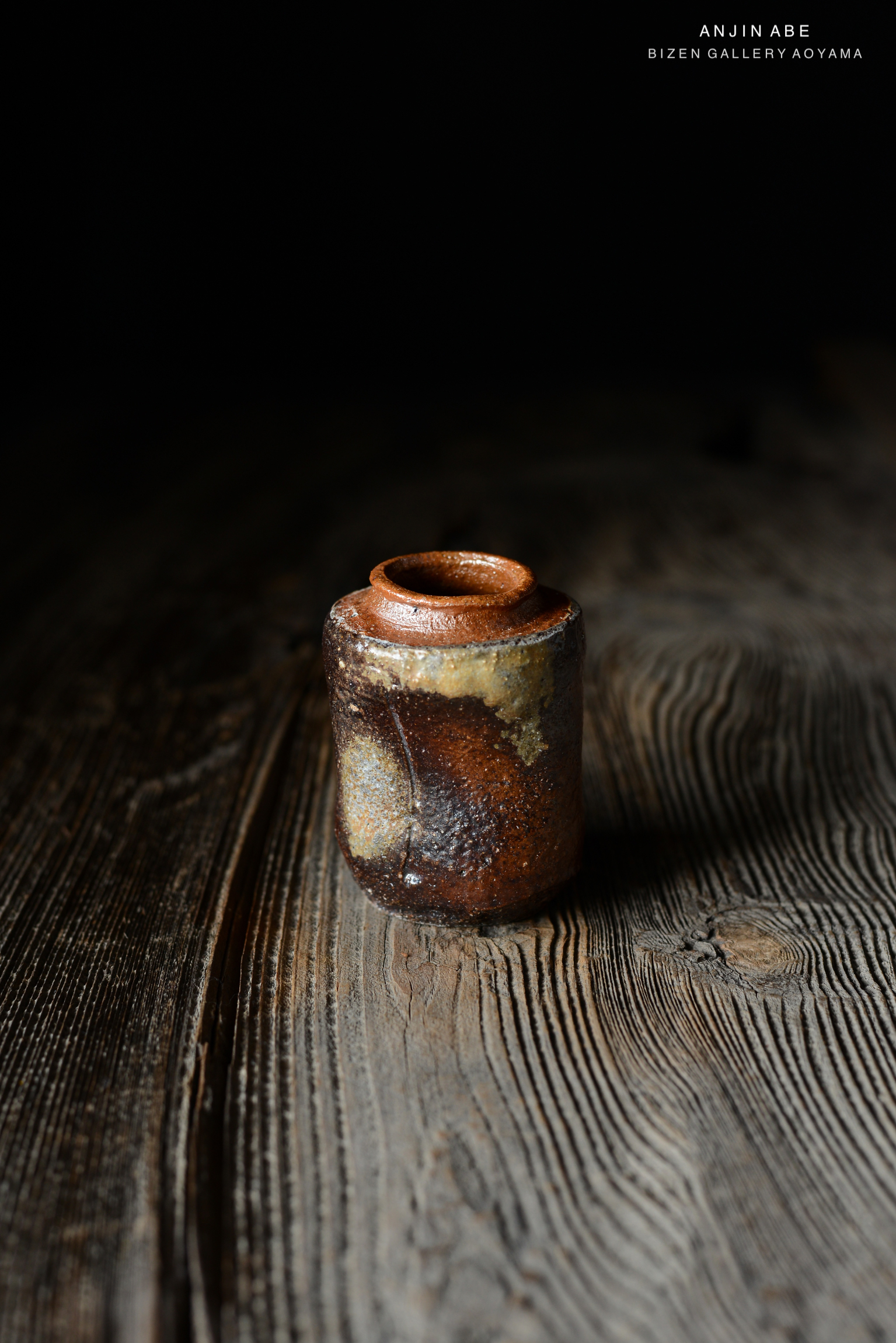 ビゼン焼きの陶器が暗い背景の上に置かれ、木製のテーブルの上に置かれている。