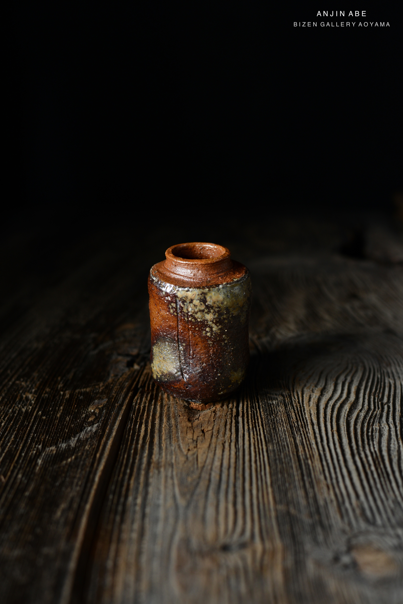 黒い背景の前に置かれた、錆びた陶器の壺