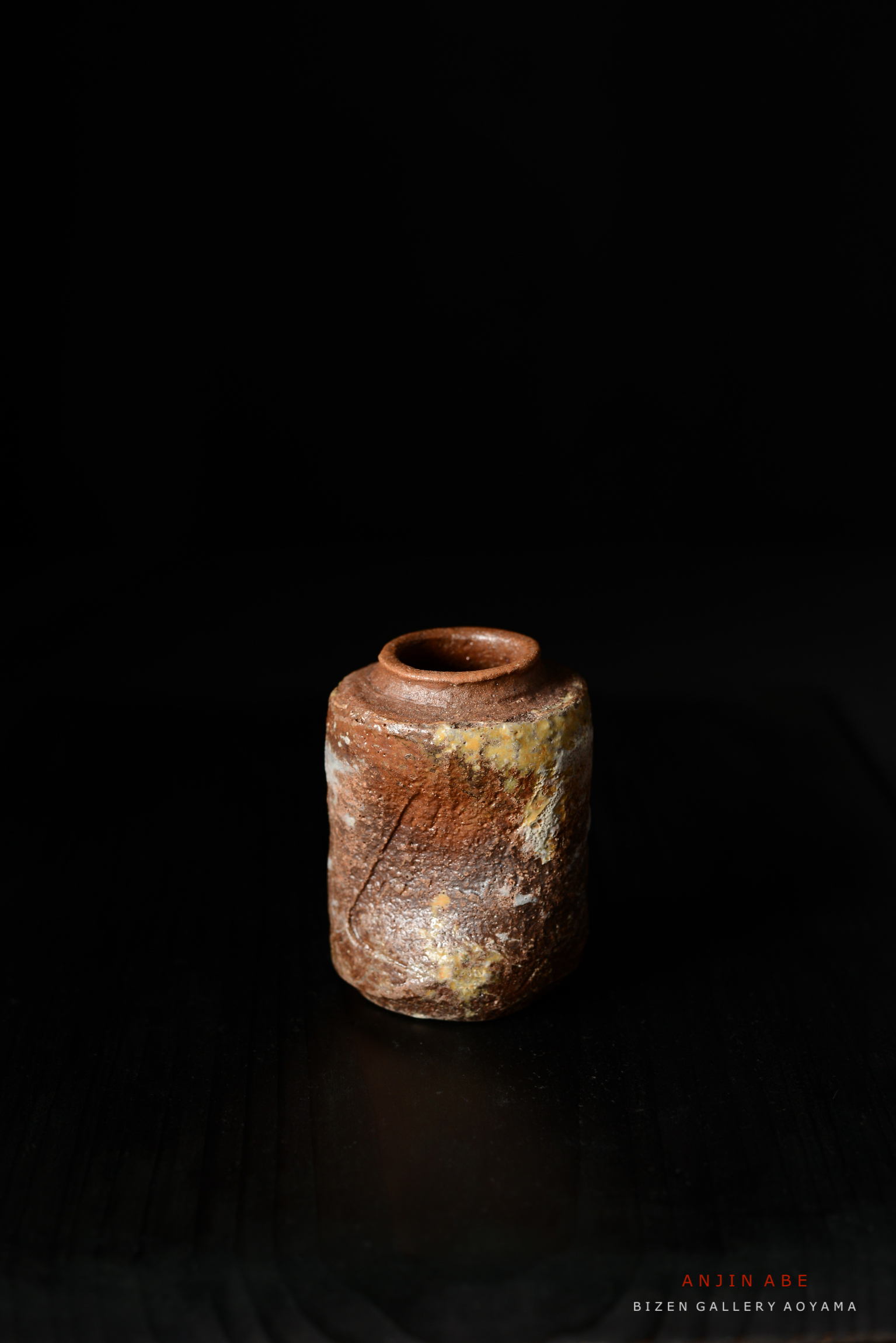 黒い背景の前に置かれた独特な形の備前焼の壺