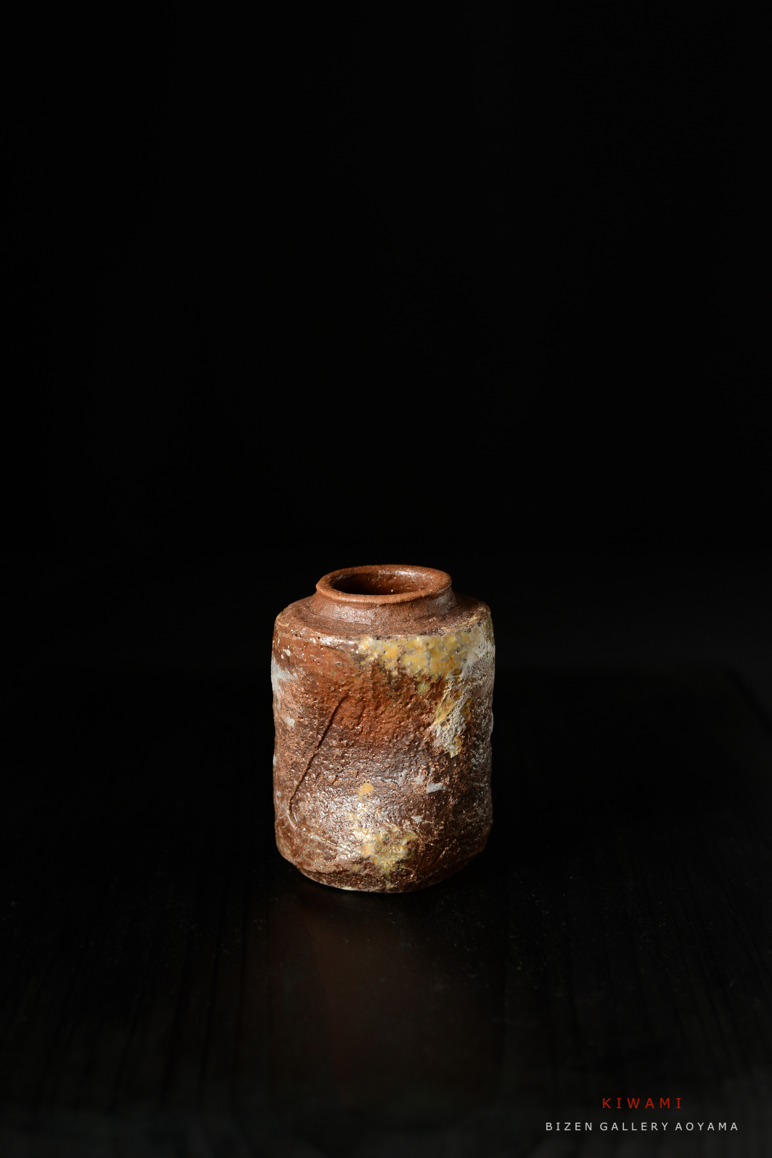 黒い背景に置かれたビゼン焼きの陶器、特徴的な色合いと質感がある。