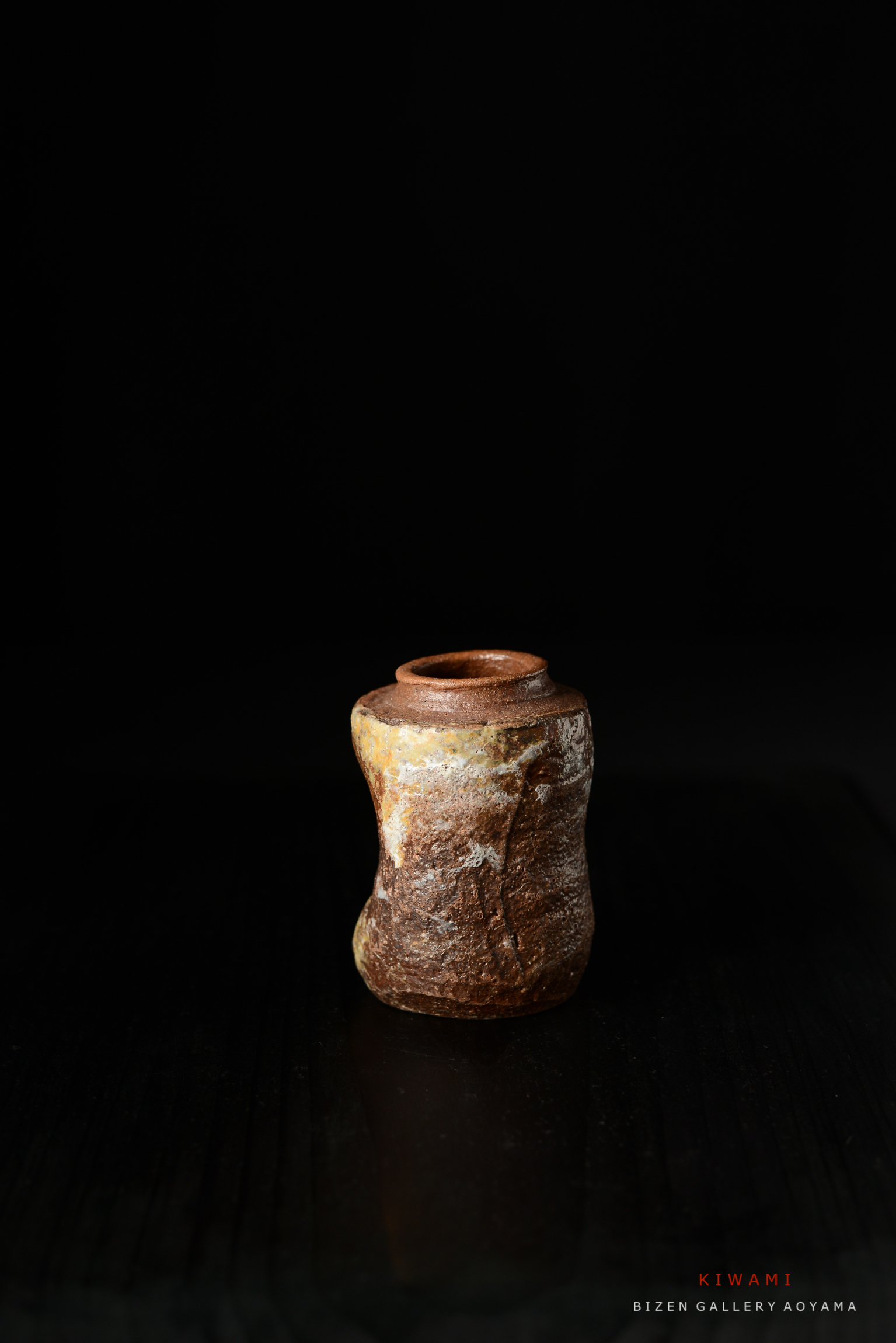 黒い背景に置かれたユニークな形状の陶器の壺。