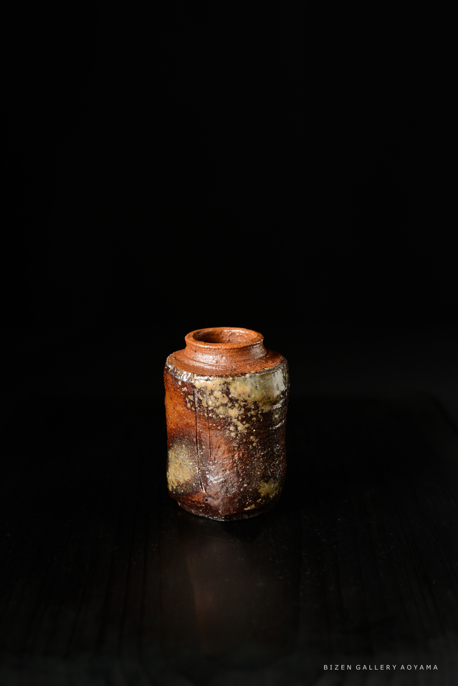 黒い背景の前に立つ焼き物の壺