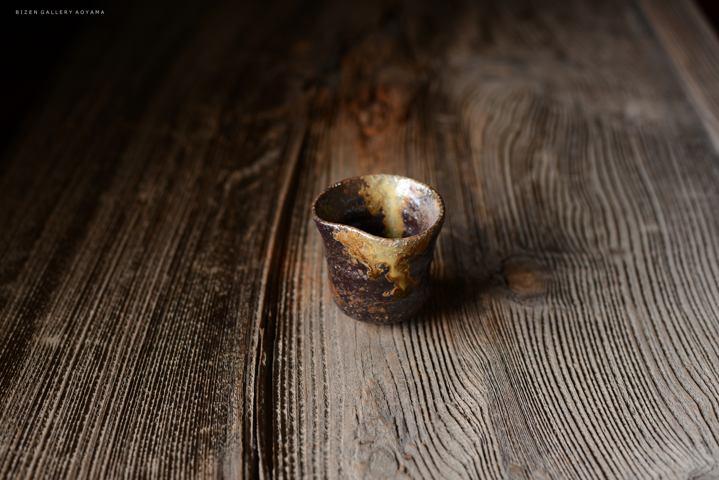 木のテーブルの上に置かれた、独特な形状の焼き物の茶碗。