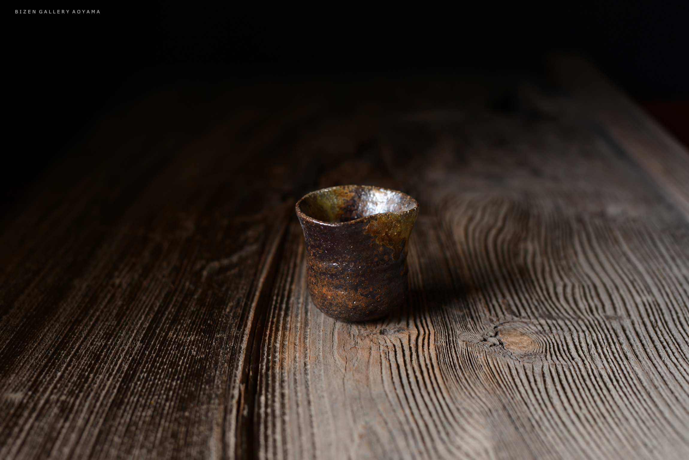 木のテーブルの上に置かれた独特な形状の陶器のカップ。