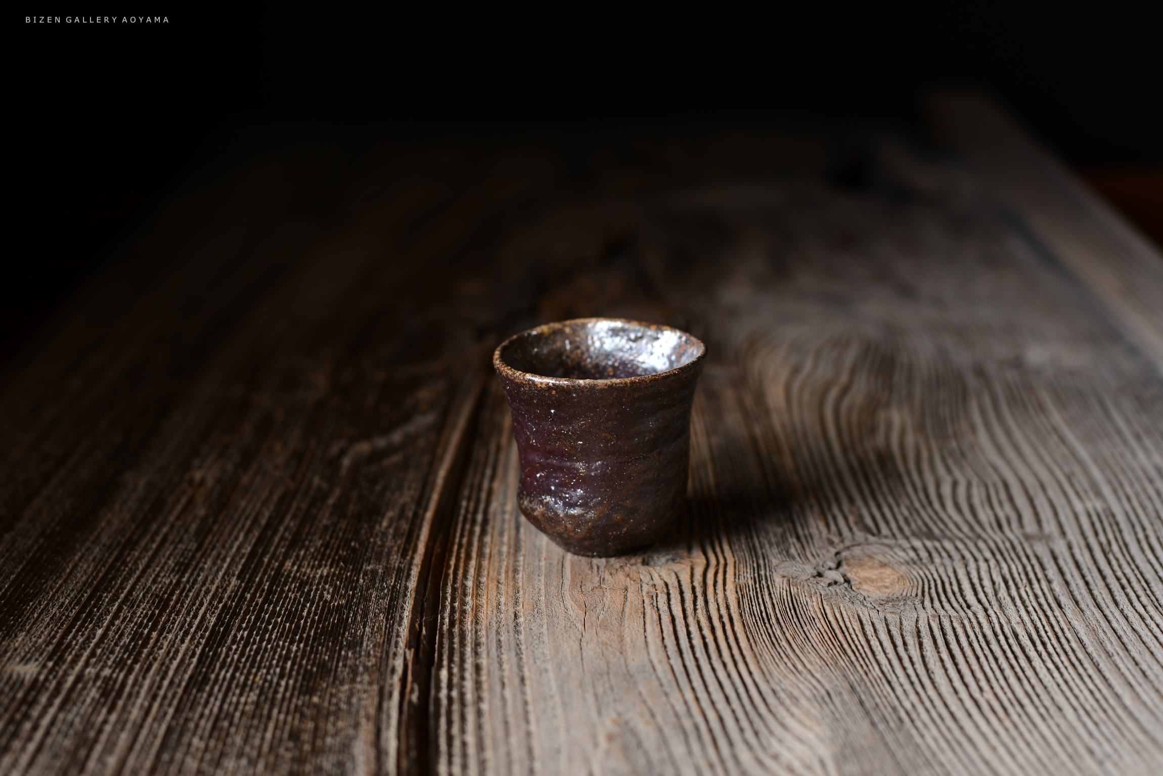 木のテーブルの上に置かれた、ビゼン焼きの陶器の小さなカップ