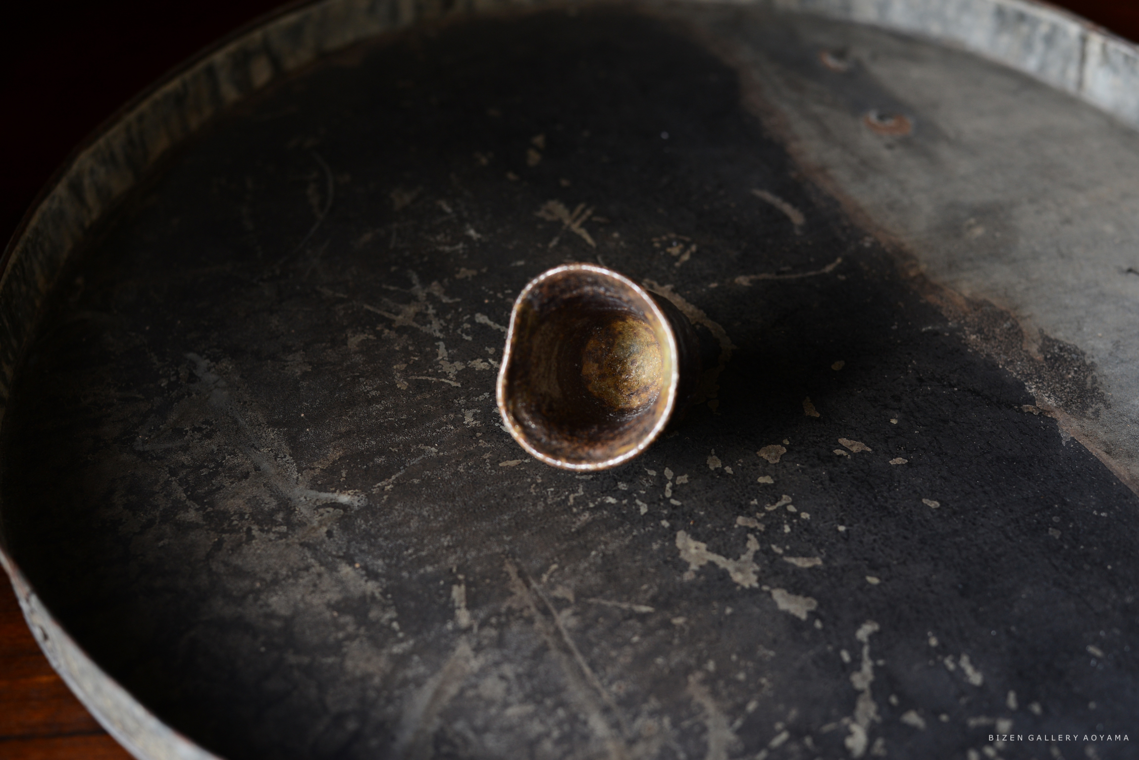 黒い皿の上に置かれた、内側が光沢のある陶器の小さな容器