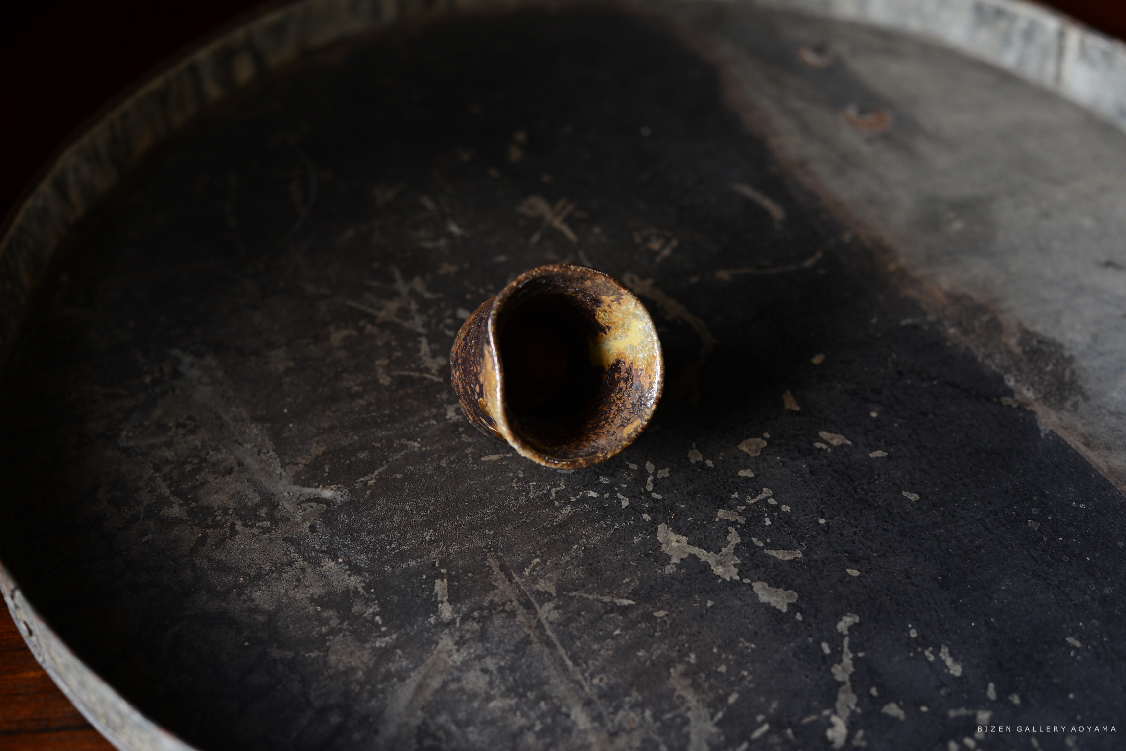 黒いテーブルの上に置かれた、内側が焦げた陶器の小さな器。