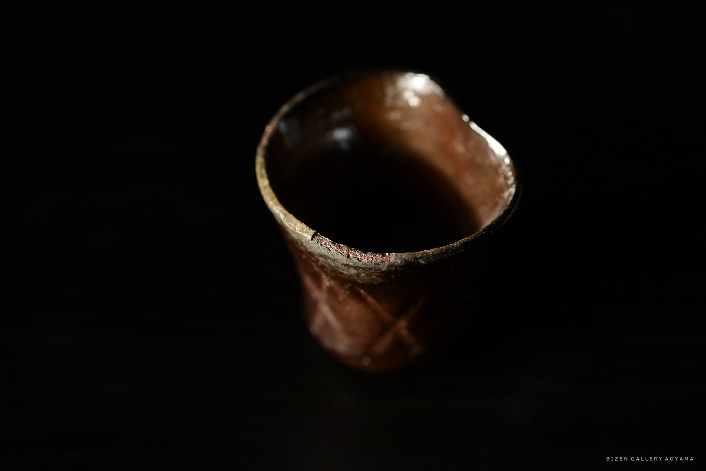 暗い背景の中に置かれた茶色の陶器のカップ。