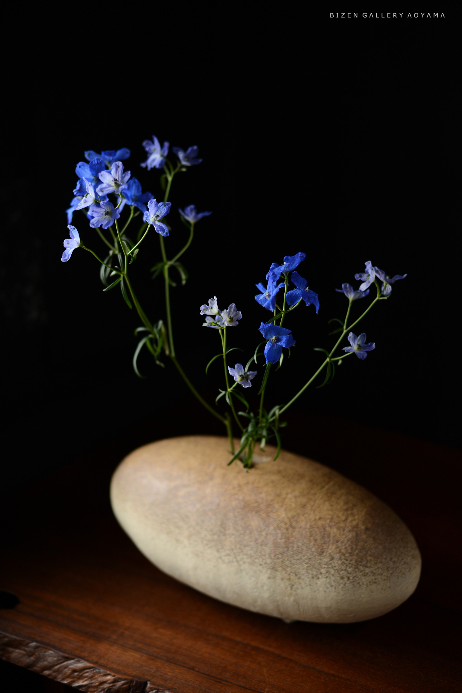 青い花々が飾られた滑らかな石の花瓶の写真