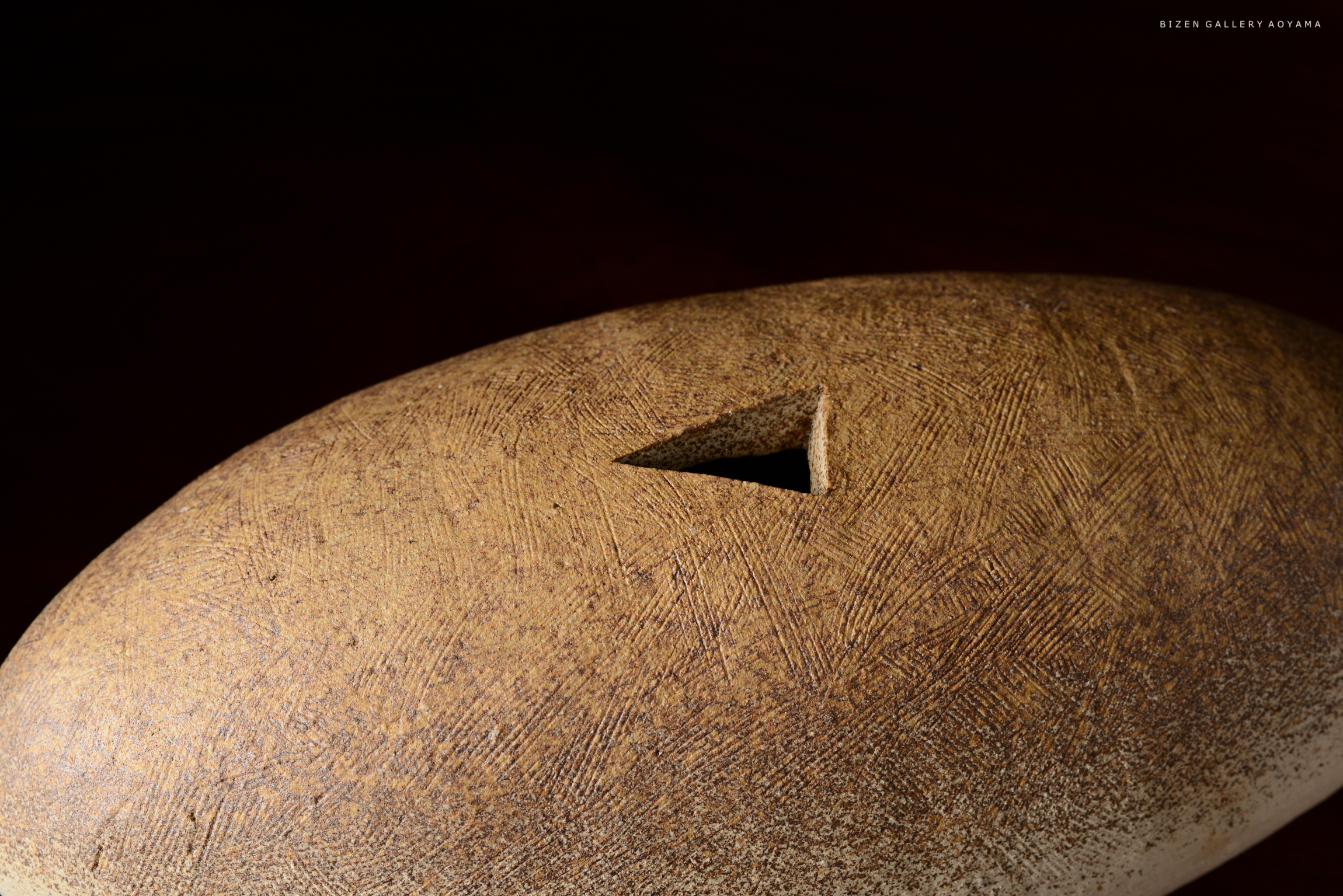 茶色の陶器の表面に三角形の穴が開いているオブジェクトのクローズアップ。