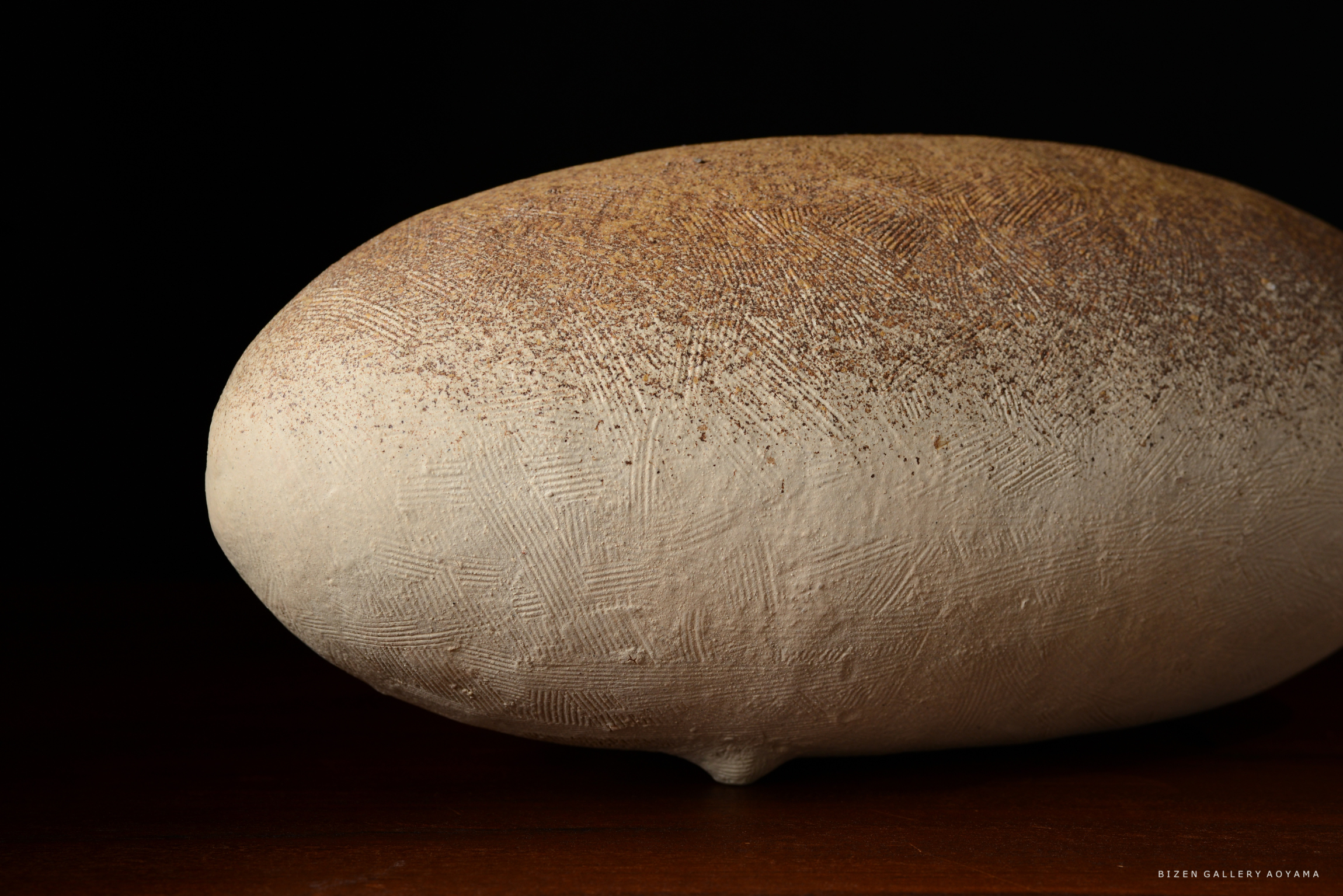 滑らかな表面を持つ白い陶器のオブジェ、上部に茶色い斑点模様が見える