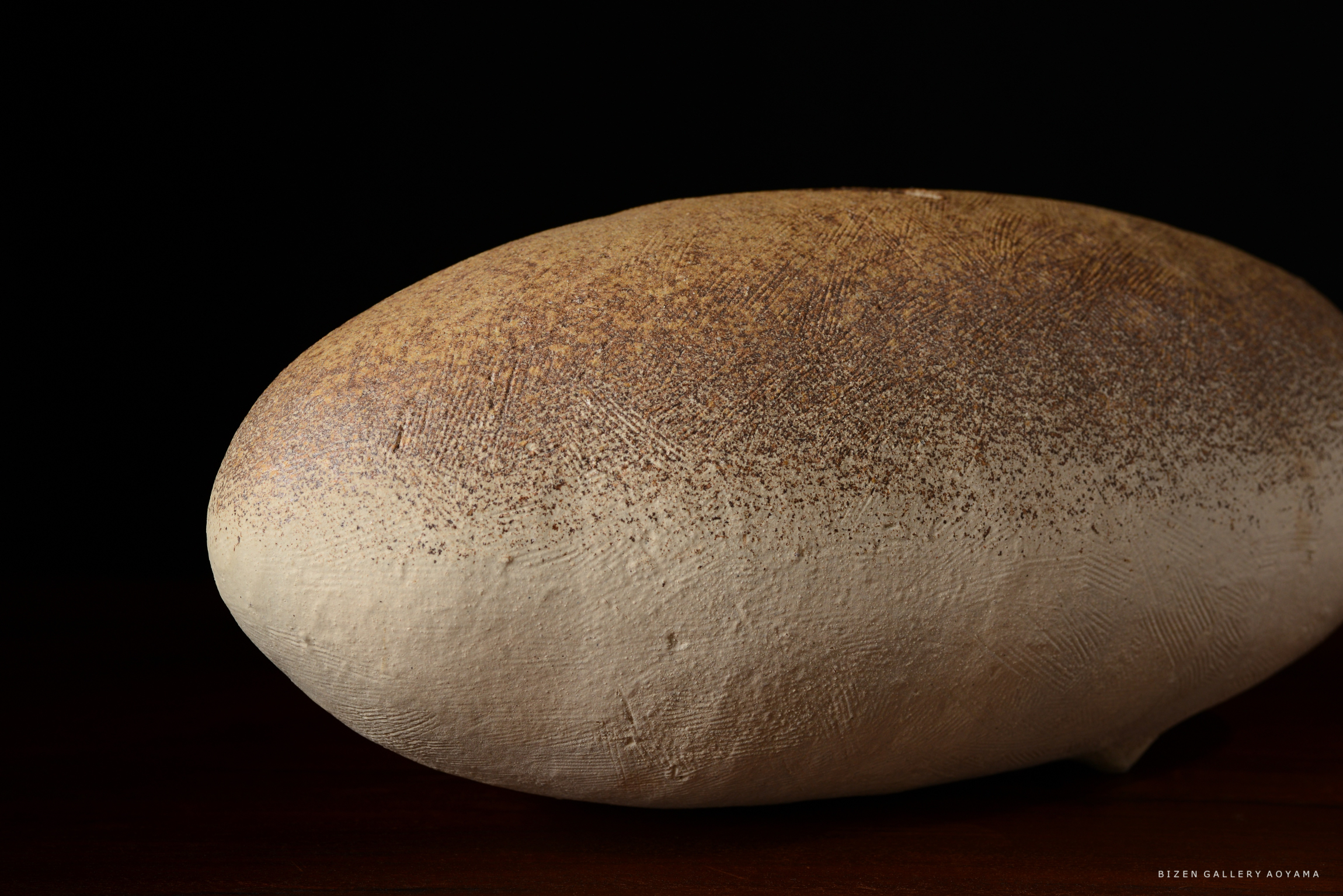 土の質感と色合いを持つ丸い陶器のオブジェ。