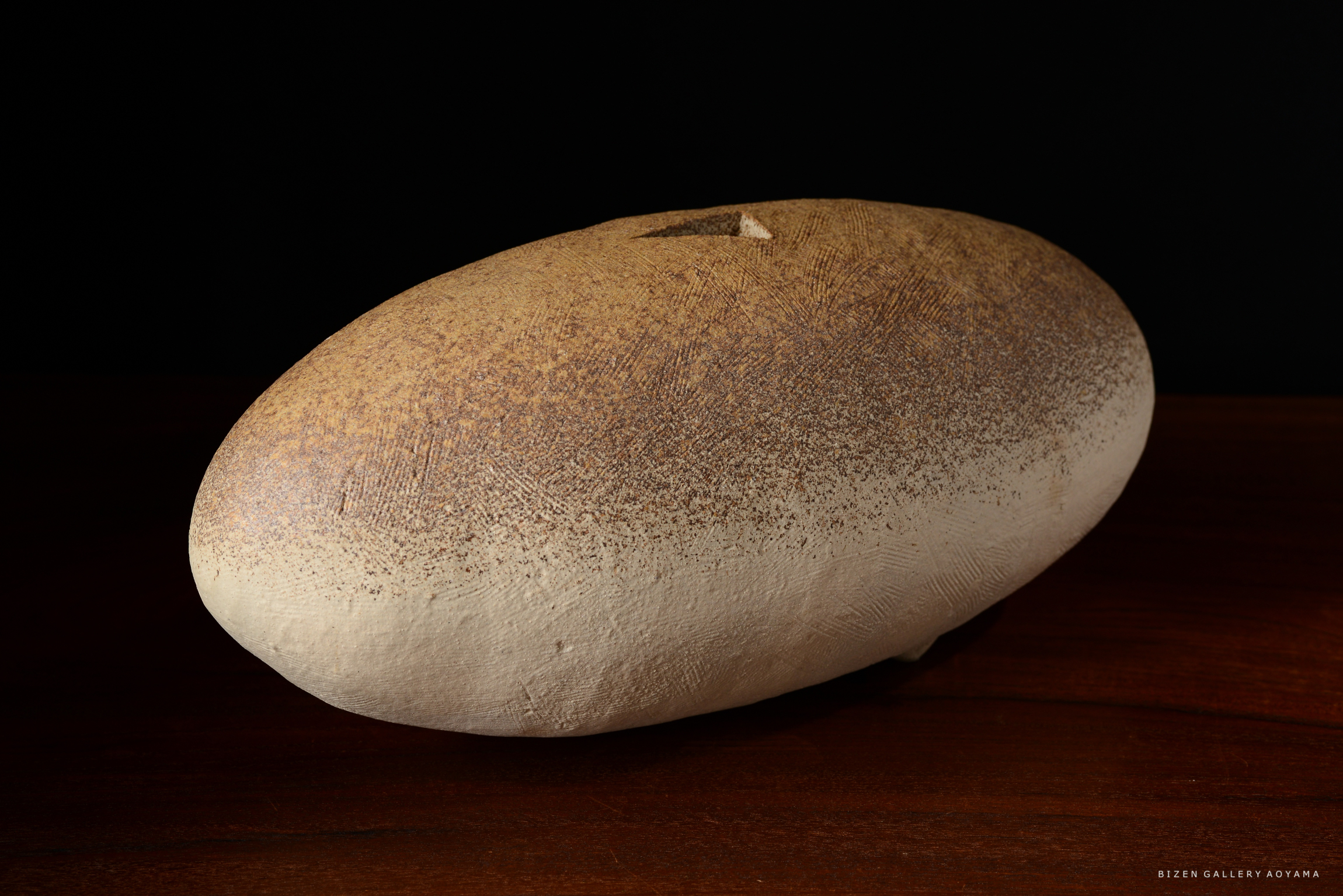 茶色の斑点模様のある陶器のオブジェが、暗い背景の上に置かれている