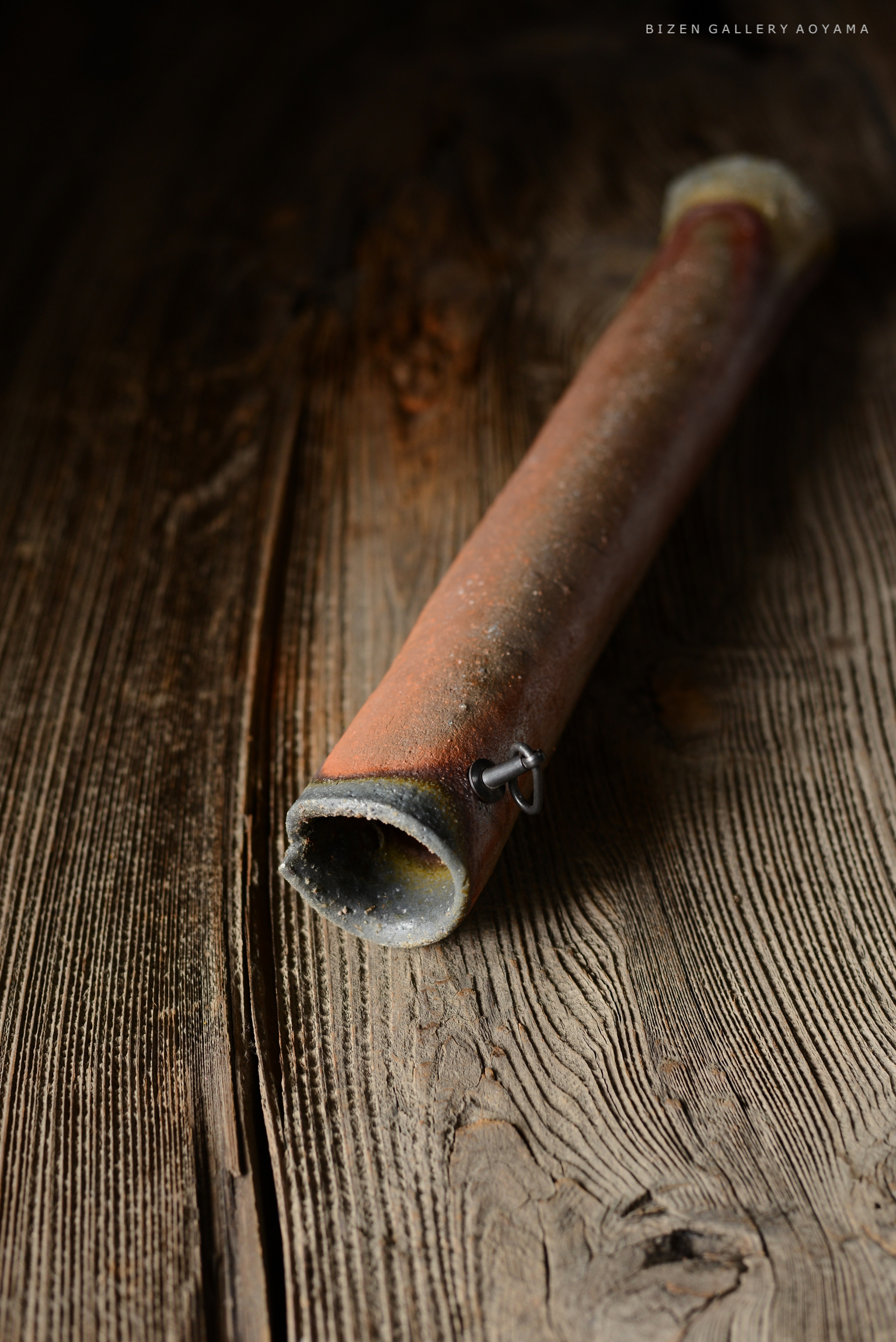 木のテーブルの上に置かれた、赤茶色の陶器の管。