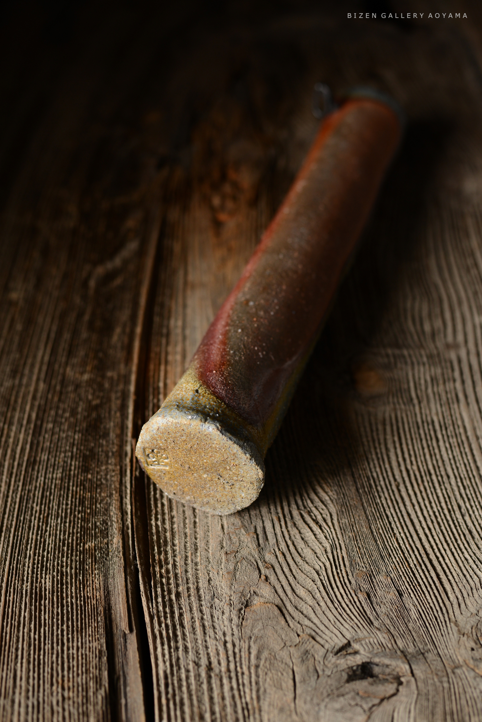 木のテーブルの上に置かれた陶器の器の底部。滑らかな表面と微妙な色合いが特徴。