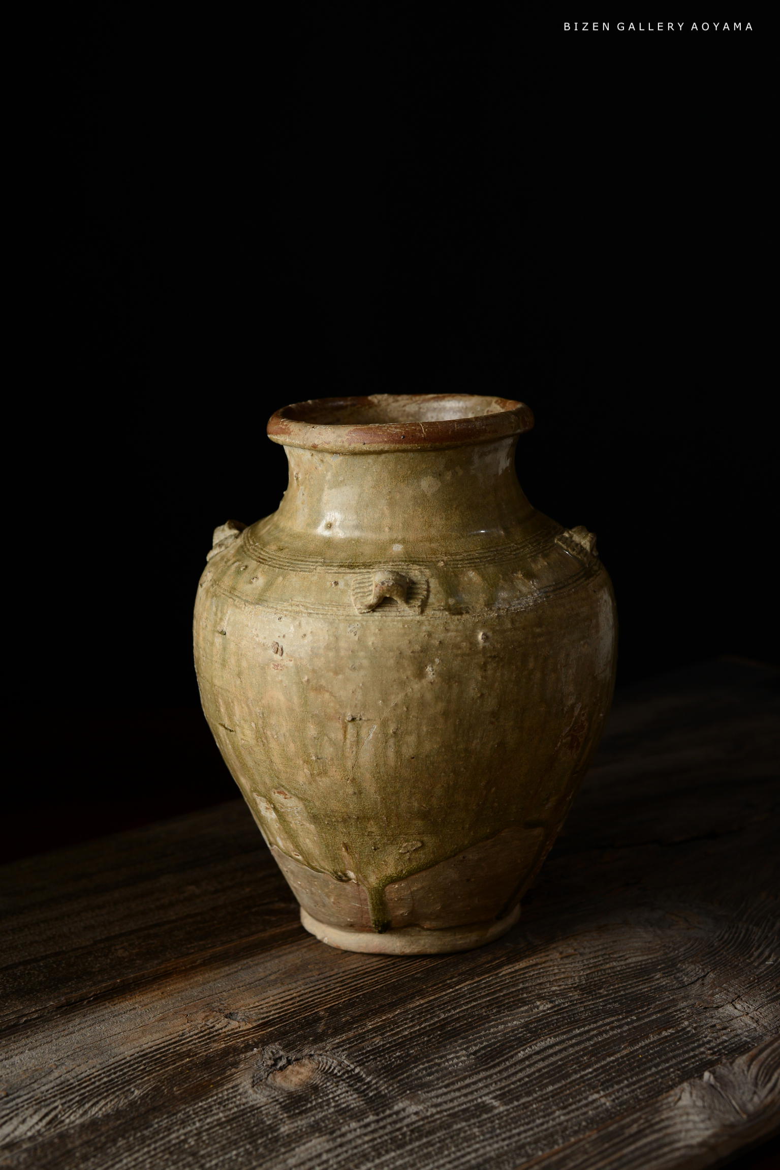 黒い背景の前に置かれたビゼン焼きの陶器の壺