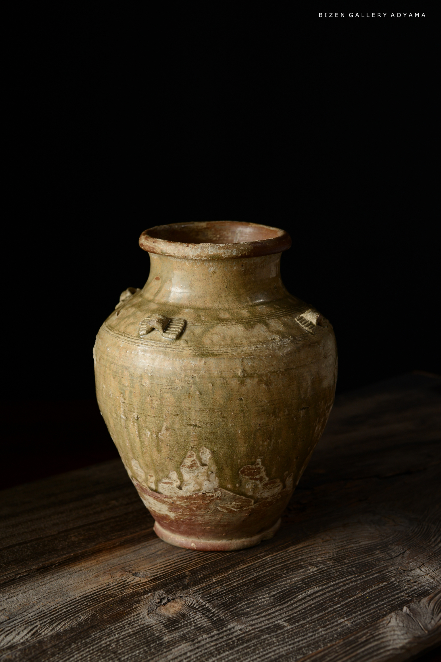 素朴な風合いの古い陶器の壺が木のテーブルの上に置かれている