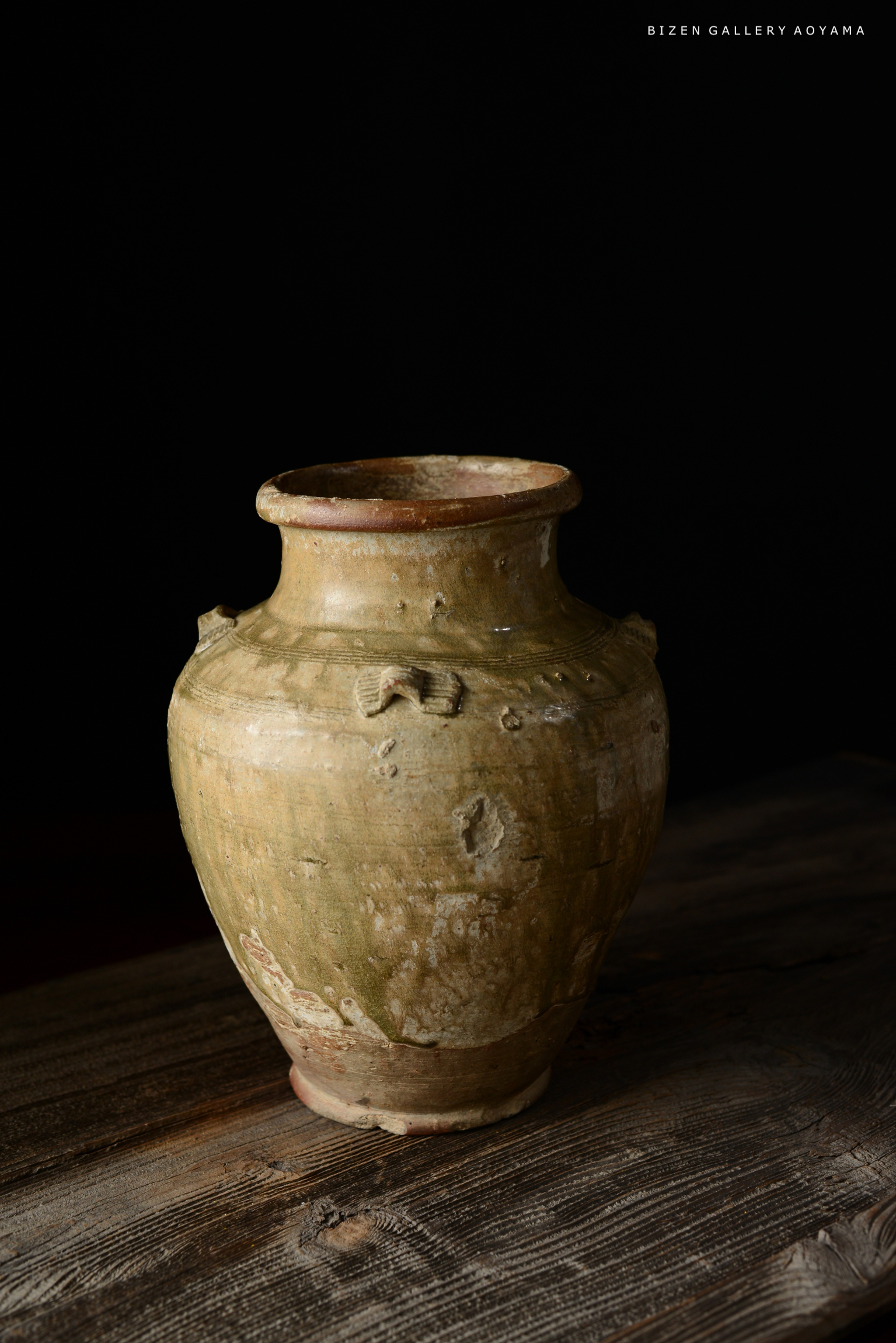 黒い背景の前に置かれたビゼン焼きの陶器の壺