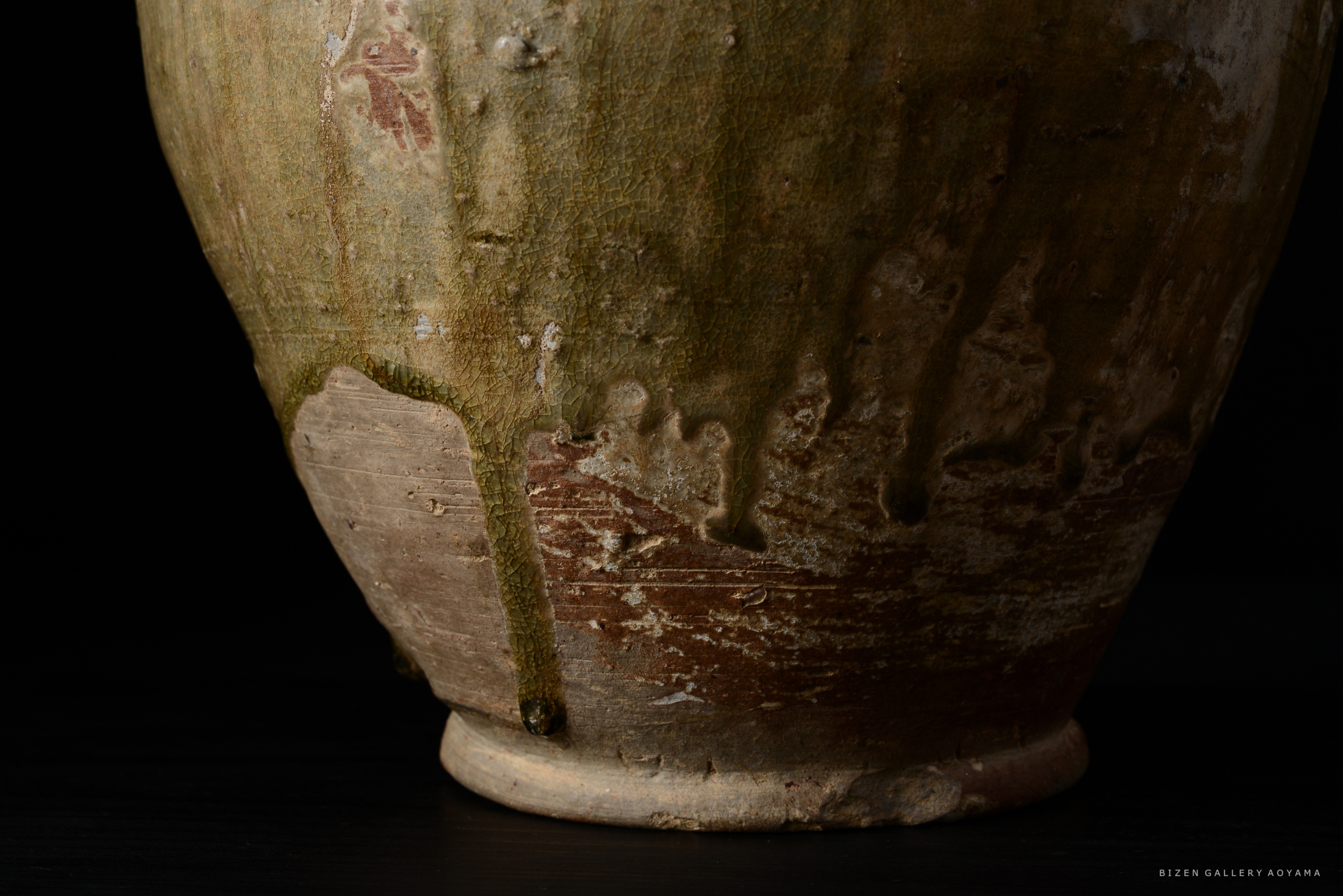 古い陶器の部分的なクローズアップ。釉薬の滴りと自然な色合いが特徴。