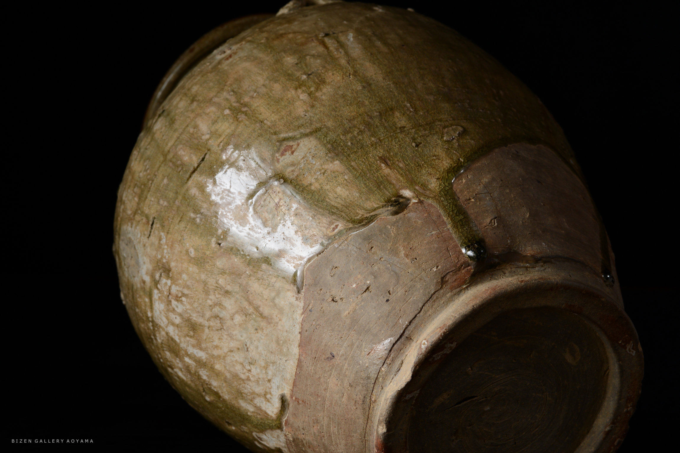 土の質感が見える、光沢のある古い陶器の壺の側面