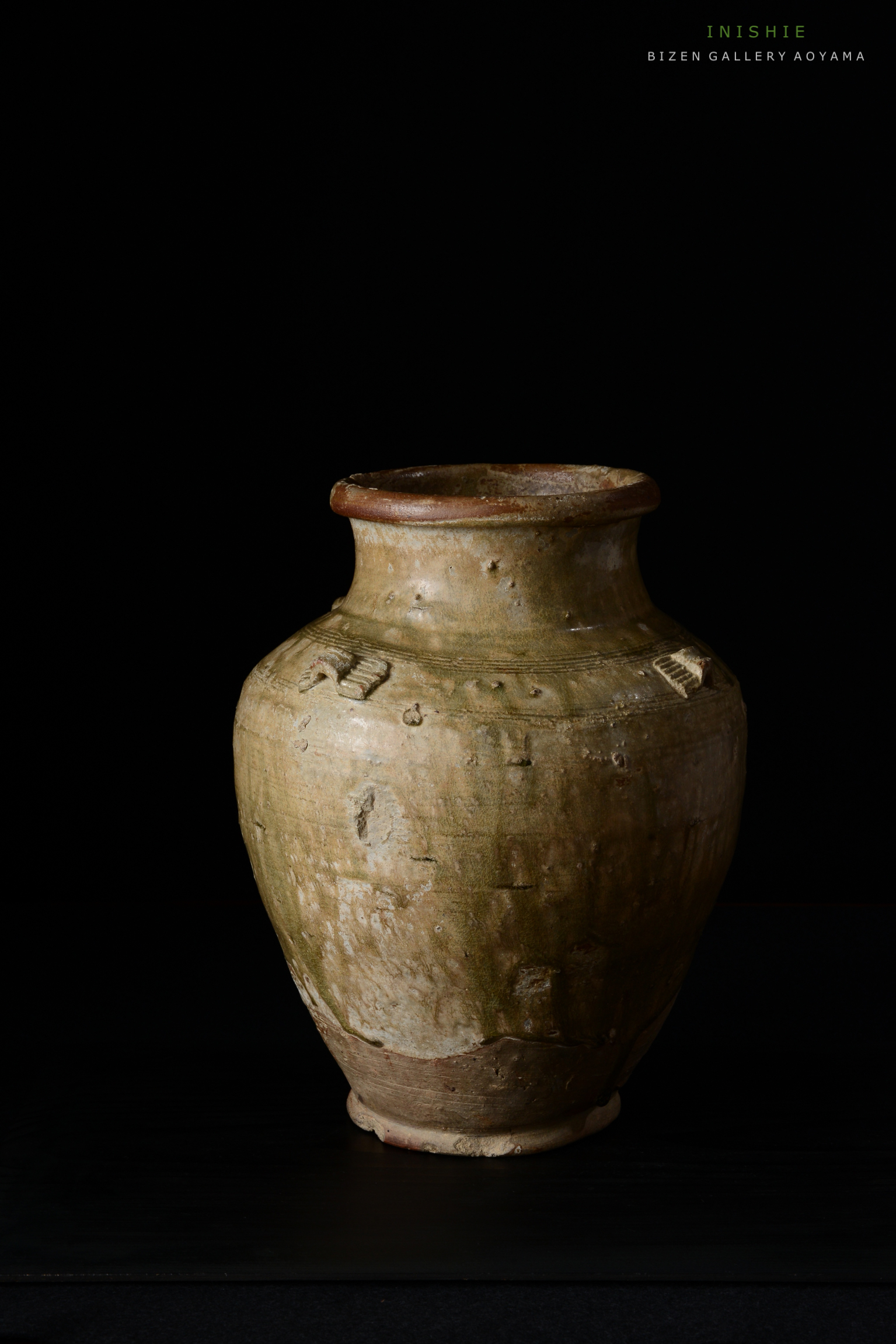 黒い背景の前に置かれた古い陶器の花瓶。表面にはテクスチャと細かい傷が見える。