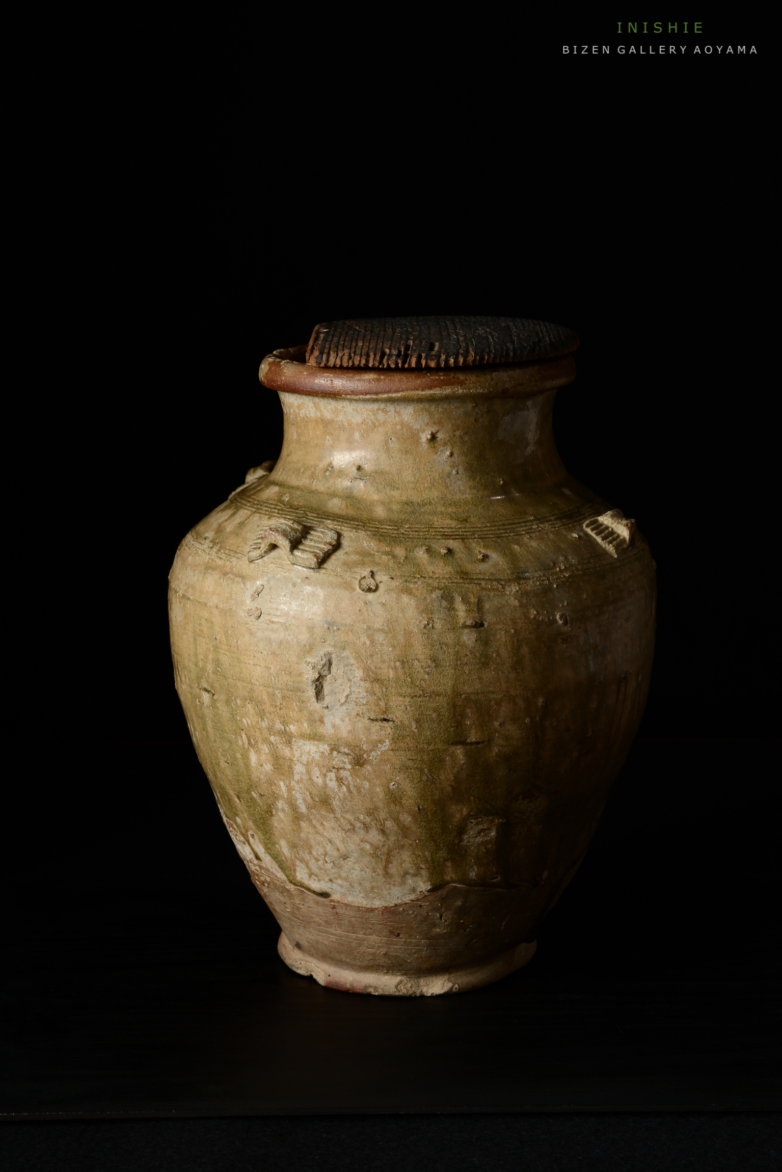 古い陶器の壺、茶色の縁と質感のある表面を持っています。黒い背景に対して立っています。